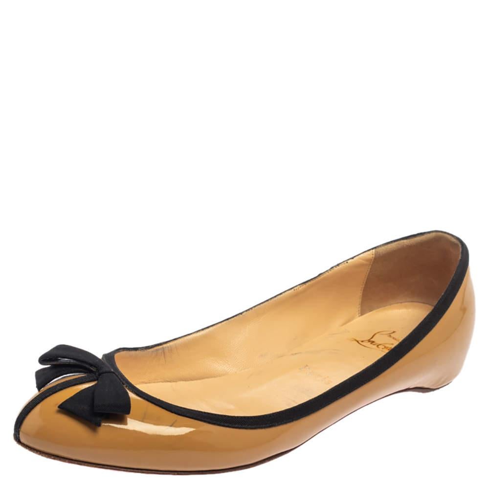 Con las emblemáticas suelas de cuero rojo, este par de bailarinas Balinodono combina sencillez y elegancia. Fabricadas en charol de color beige, tienen puntera redonda con ribete de grosgrain negro y detalle de lazo de esmoquin en la parte superior.