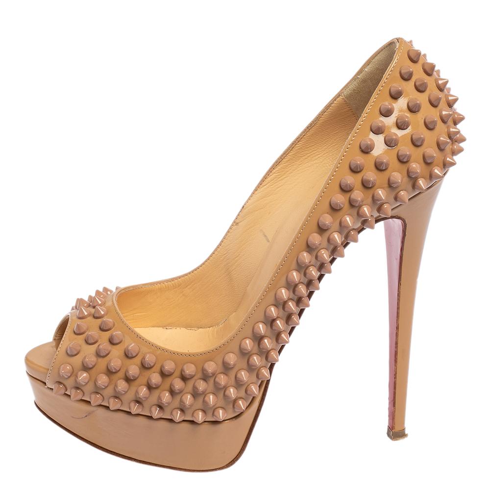 Make a statement in this pair of Christian Louboutin pumps! Crafted from patent leather, this is a creation from their Lady Peep collection. The pumps feature a beige shade with peep toes and a spike-embellished exterior. Completed with leather