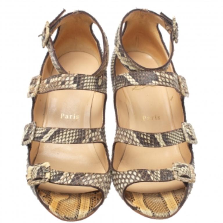 These stylish sandals hail from the house of Christian Louboutin. They have been crafted from exotic python and come in a lovely shade of beige. They have a caged silhouette, open toes, buckled straps, silver-tone hardware, and 8 cm wedge heels.