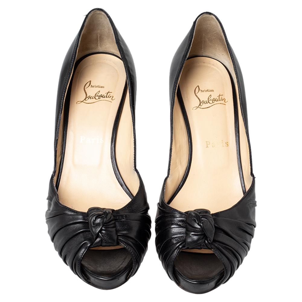 Crafted from black leather and styled with peep toes, these Christian Louboutin pumps will lift you beautifully. The pumps highlight ruched knotted low vamps and 8.5 cm heels. They are given a finishing touch with the signature red lacquer soles.

