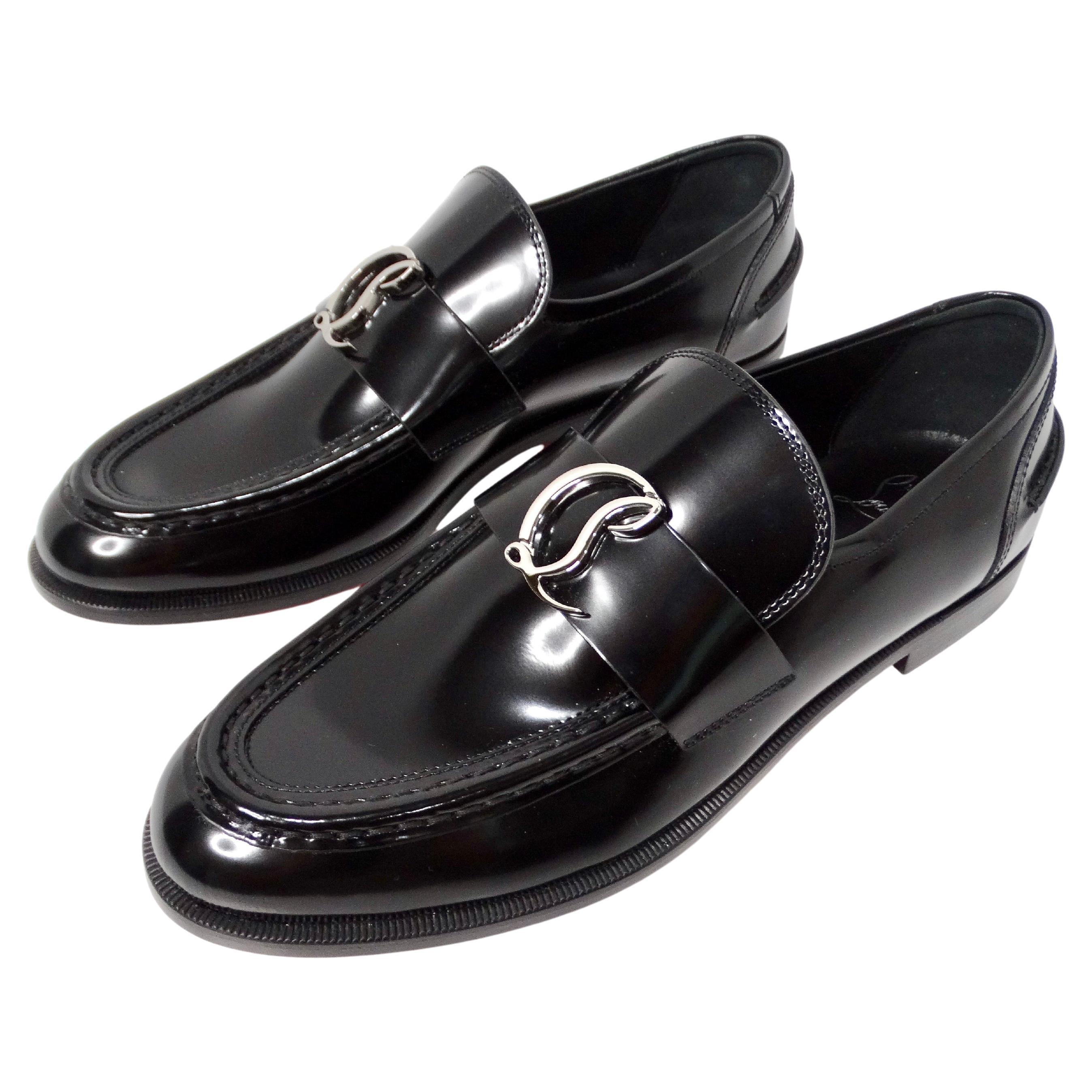 I mocassini piatti con logo in vernice nera di Christian Louboutin sono una scelta di calzature sofisticata e versatile che combina perfettamente l'eleganza classica con l'avanguardia moderna. Realizzati in elegante pelle verniciata nera, questi