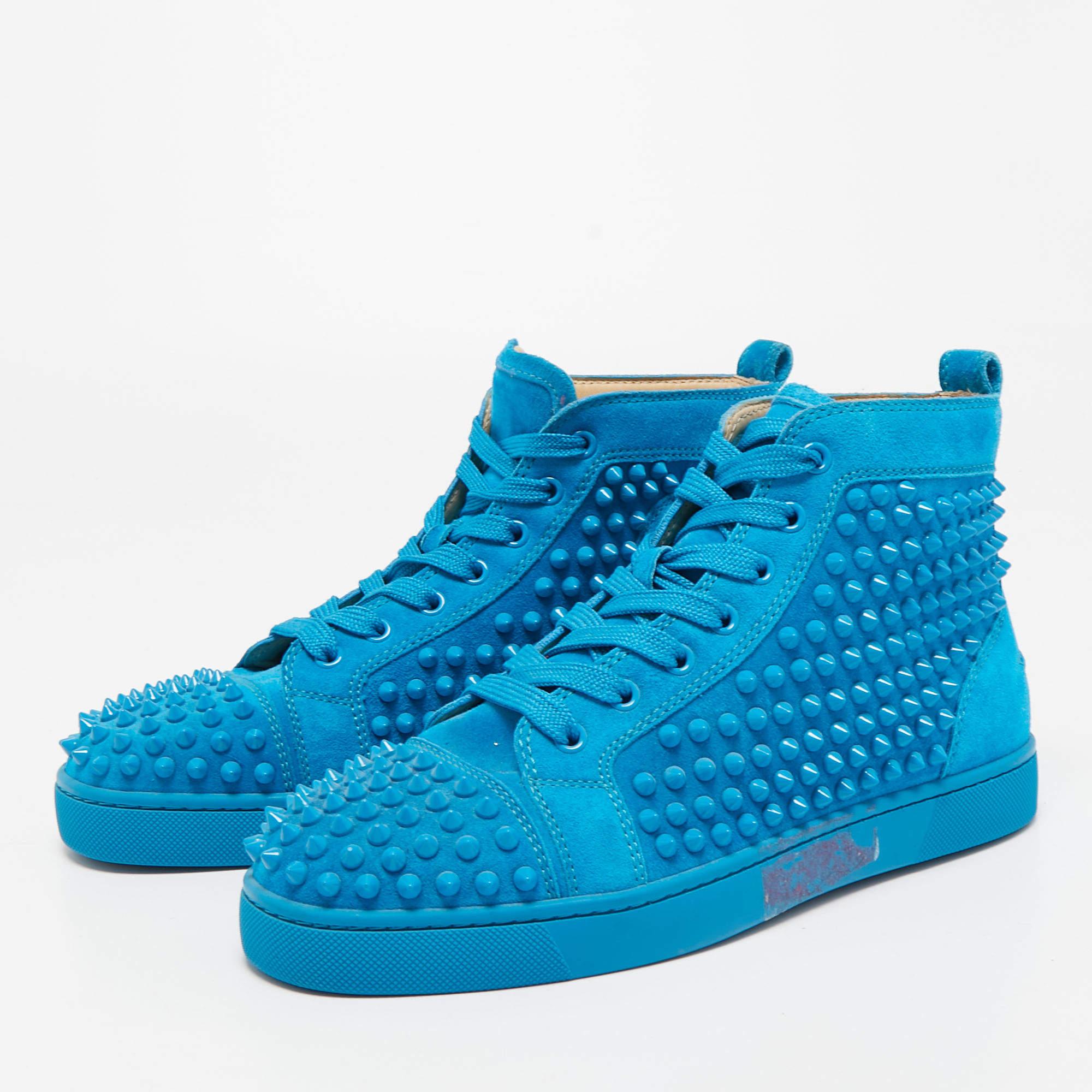 The Christian Louboutin sneakers combine luxurious craftsmanship with edgy details. Made from premium blue suede, these high-top sneakers feature signature spike embellishments on the toe cap and sides, adding a touch of rebellious sophistication.