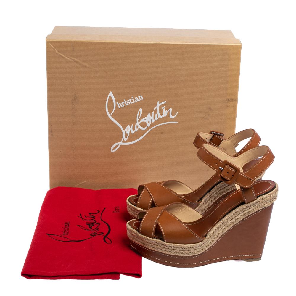 Set on towering wedge heels, these sandals from the house of Christian Louboutin feature brown leather cross straps over the toes, buckle fastening at the ankles, and leather-lined insoles detailed with the brand label. The Almeria sandals are