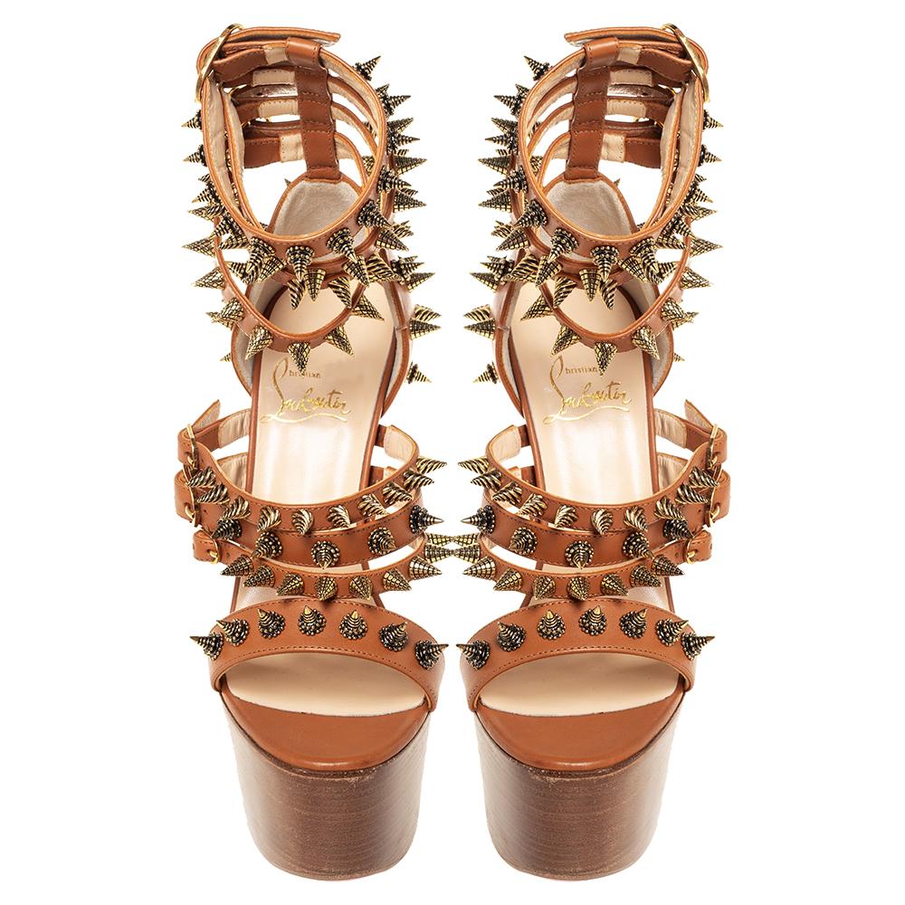 On a brown leather construction featuring straps adorned with multiple spikes, these Louboutins surely stand out! Endowed with comfortable leather-lined insoles, these beauties soar high with their solid platforms and 15 cm heels. They carry the