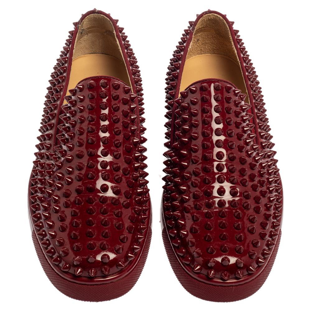 Make an amazing style statement in these slip-on sneakers from Christian Louboutin. They have been crafted from burgundy patent leather and styled with round toes. They are adorned with spike embellishments all over the exterior and come equipped