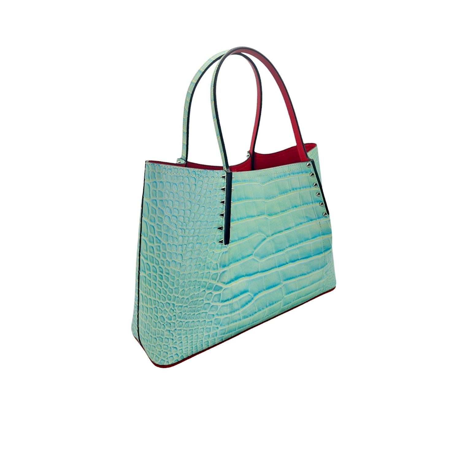 Elevate your style with the exquisite Christian Louboutin Crocodile Embossed Cabarock Spiked Leather Tote. Crafted in Italy, this luxurious tote features embossed crocodile leather in a striking Studio Green color. The leather strap handles are