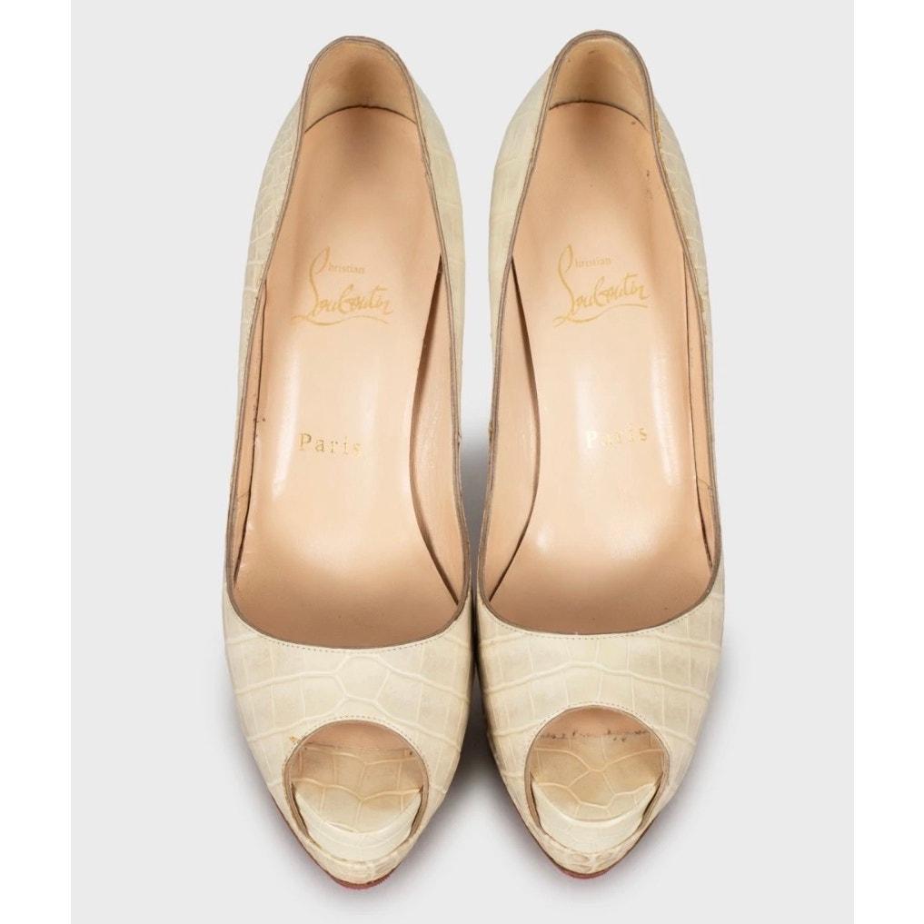 ¡Sal a la calle con estilo con estos elegantes zapatos de salón Christian Louboutin! Estos impresionantes zapatos presentan cuero beige repujado, un elegante tacón de cuña y un diseño peep-toe. Perfecto para añadir un toque de sofisticación a
