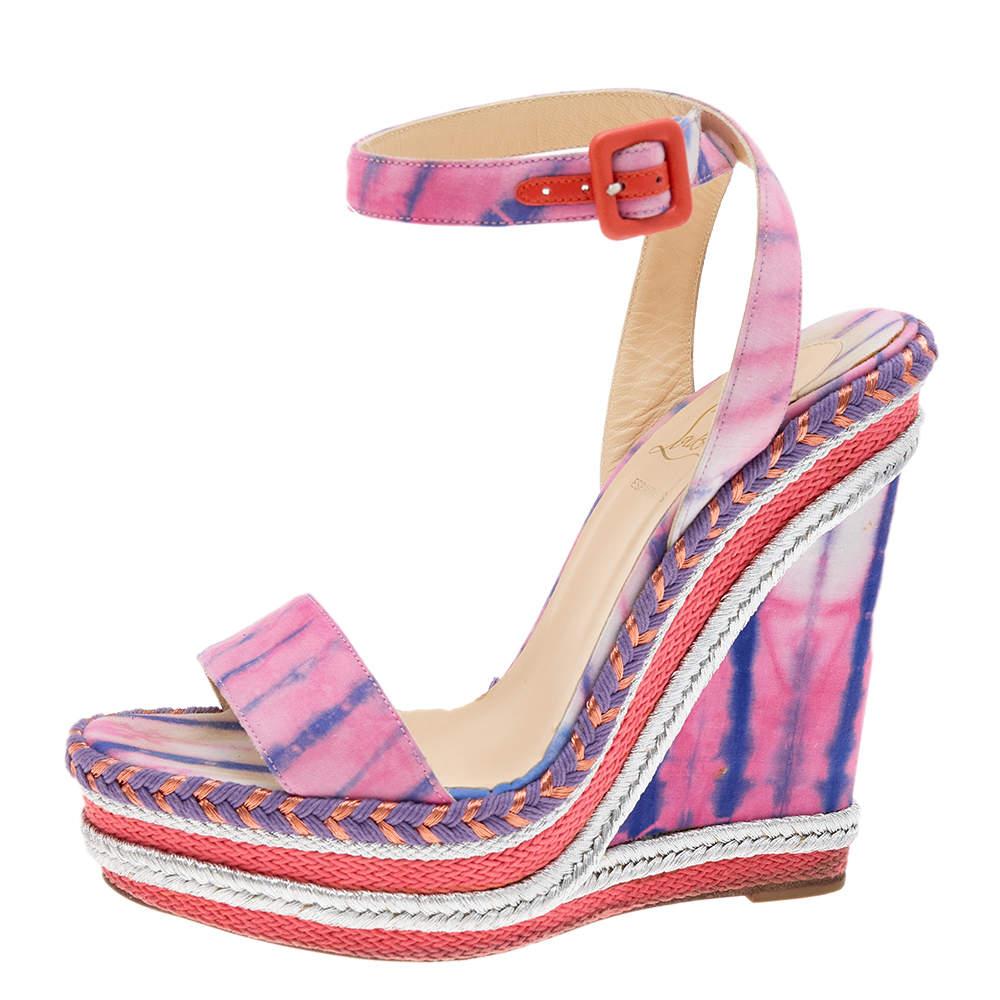 These sandals from the House of Christian Louboutin are pretty and poised. Made from multicolored fabric these sandals flaunt platform wedge heels and an ankle strap feature. They are provided with buckled closure and red soles. Complement your