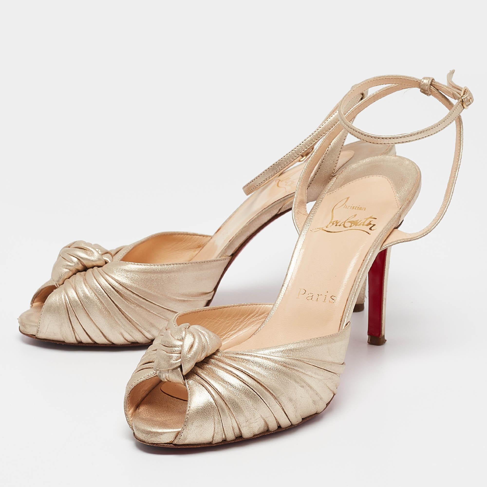 Sono bellissimi questi sandali di Christian Louboutin. Sono rivestiti in pelle dorata e presentano un nodo arricciato sulla tomaia. Queste décolleté hanno un plateau con tacco di 10 cm e la caratteristica suola rossa. Lascia che questo paio di