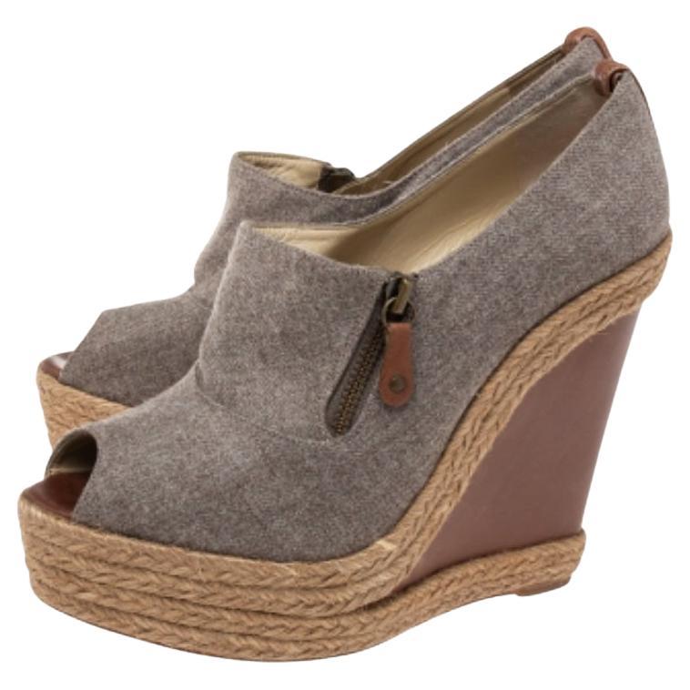 Elevate your fashion game with these gorgeous Christian Louboutin sandals. The grey pair is crafted from wool and comes with pretty zippers. It is skillfully finished with peep-toes, sturdy leather soles, and towering 14.5 cm wedge heels.