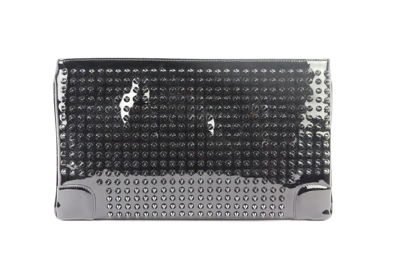 This ‘Loubiposh’ clutch by Christian Louboutin ha the brands signature studs that give the tough-luxe embellishments a fresh new look, the rest of the bag is made from patent leather with large internal zip compartment. Black patent leather. Zip