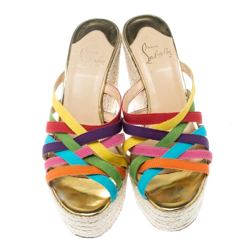 Absolutely on-trend and easy to flaunt, this pair of wedge sandals by Christian Louboutin is a true stunner. They've been styled with multicoloured crisscross fabric straps. They are complete with 11 cm espadrille wedges and the signature red