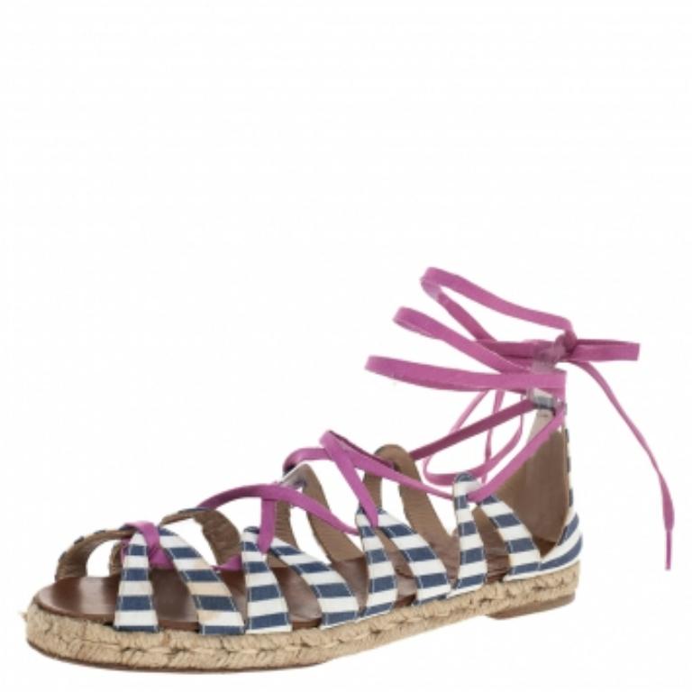 Enjoy summer in fashionable comfort with these Christian Louboutin espadrille flat sandals. Made from striped fabric, the sandals are laced with pink strings that end as ankle ties.