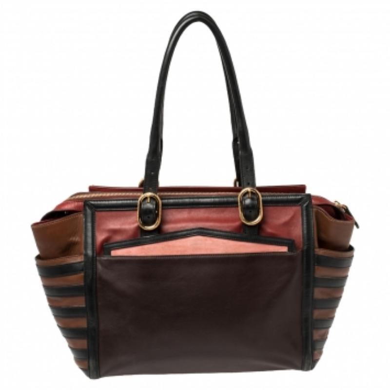 Featuring dual buckle handles and multiple hues, this Christian Louboutin tote exudes just the right amount of sophistication. The leather bag comes equipped with a capacious fabric interior to house all your daily essentials. Flaunting the brand
