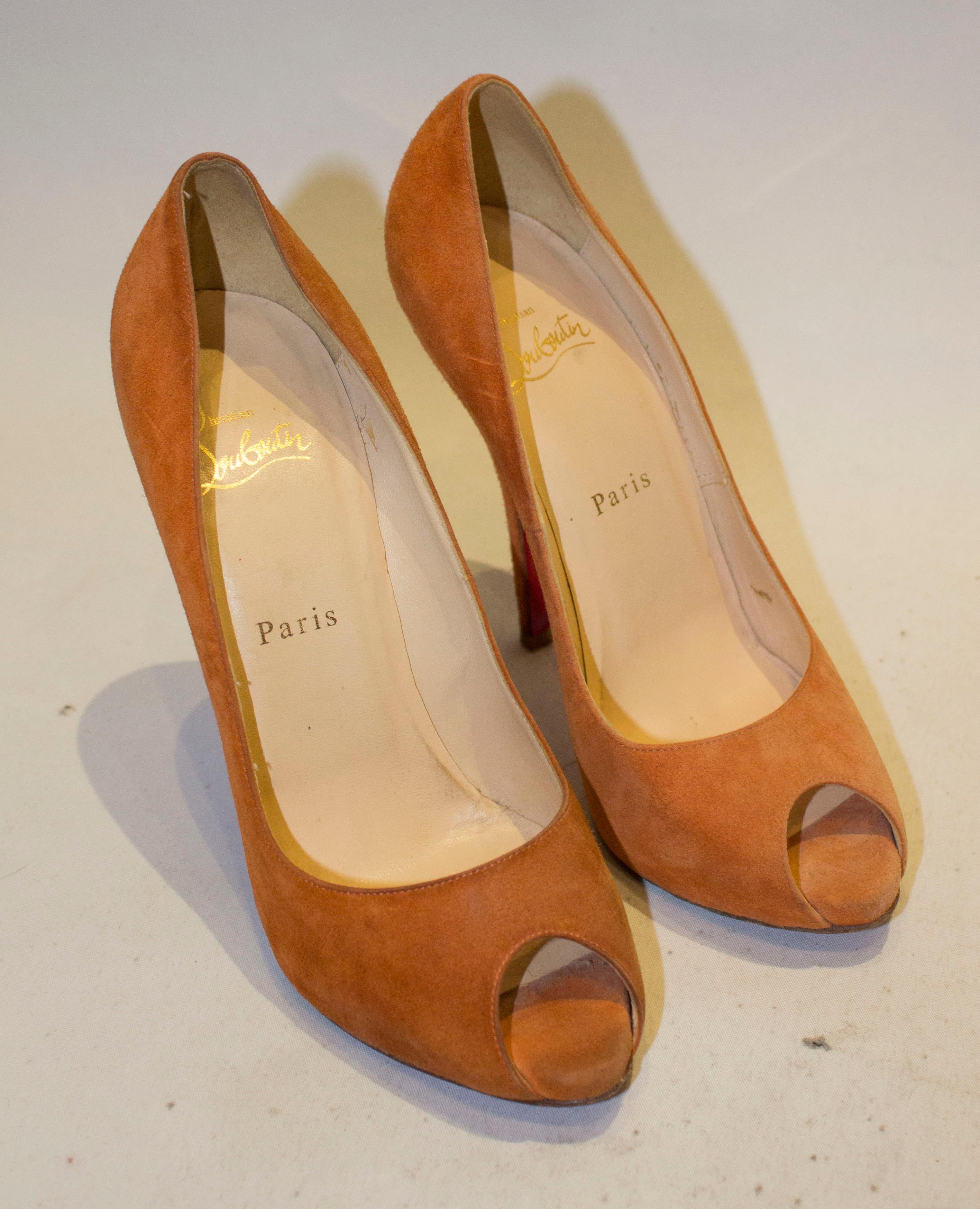 A great pair of heels by Christian Louboutin. The shoes are in an orange suede with leather soles, hidden platform and peep toes. Size 37 1/2 heel height  5''