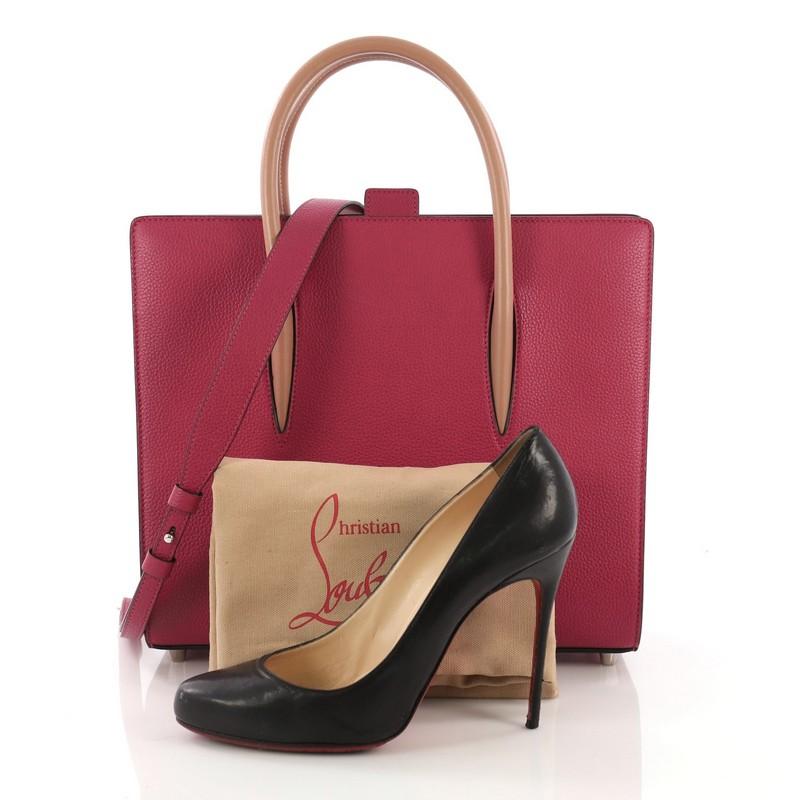 This Christian Louboutin Paloma Tote Leather Medium, crafted in pink leather, features dual rolled leather handles, spiked patent leather on the sides, protective base studs, and silver-tone hardware. Its tab closure opens to a red leather interior.