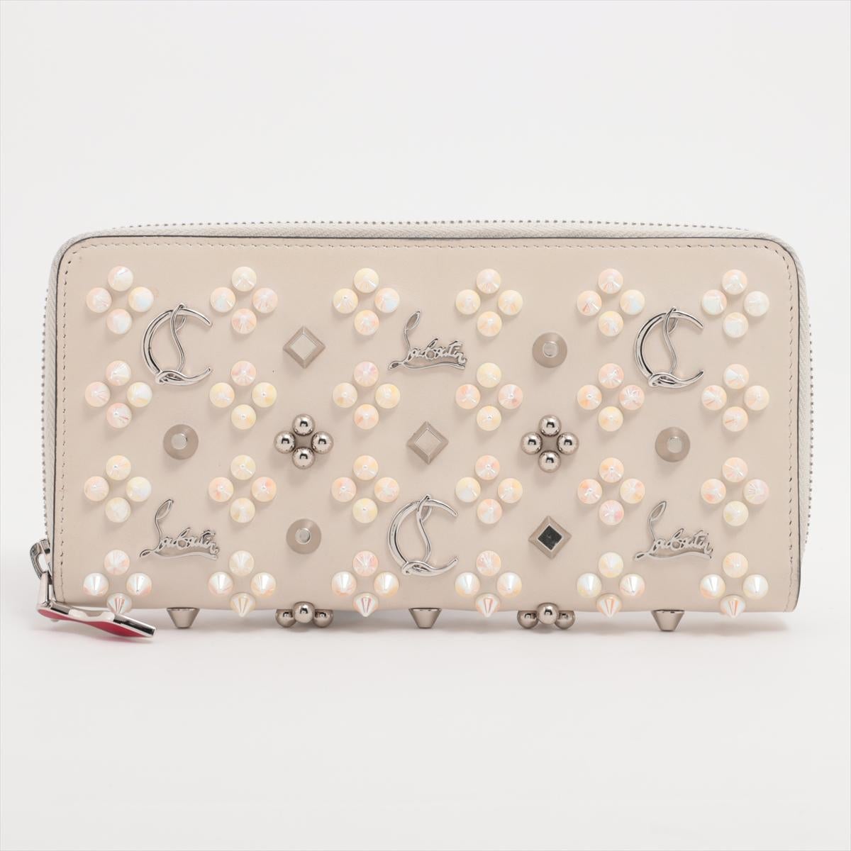 The Christian Louboutin Panettone Rock Studs Leather Zip Round Wallet in Ivory is a bold yet sophisticated accessory that exudes modern elegance with an edgy twist. Crafted from smooth ivory leather, the wallet is adorned with signature tonal rock