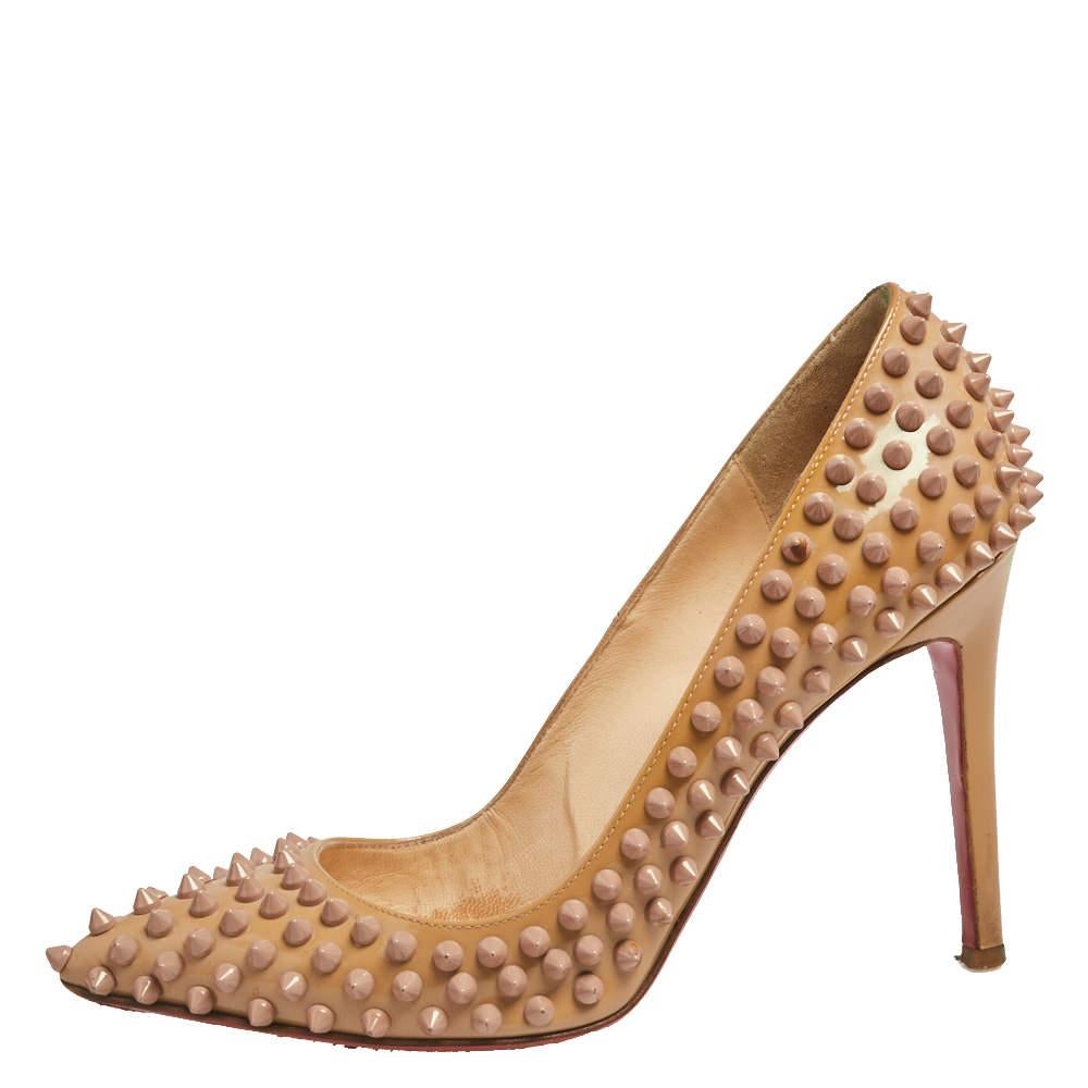 Dazzle everyone with these Louboutins! Crafted from patent leather, these beige pumps carry a mesmerizing shape with pointed toes, multiple spikes adorning the exterior, and 10.5 cm heels. Complete with the signature red soles, this pair truly