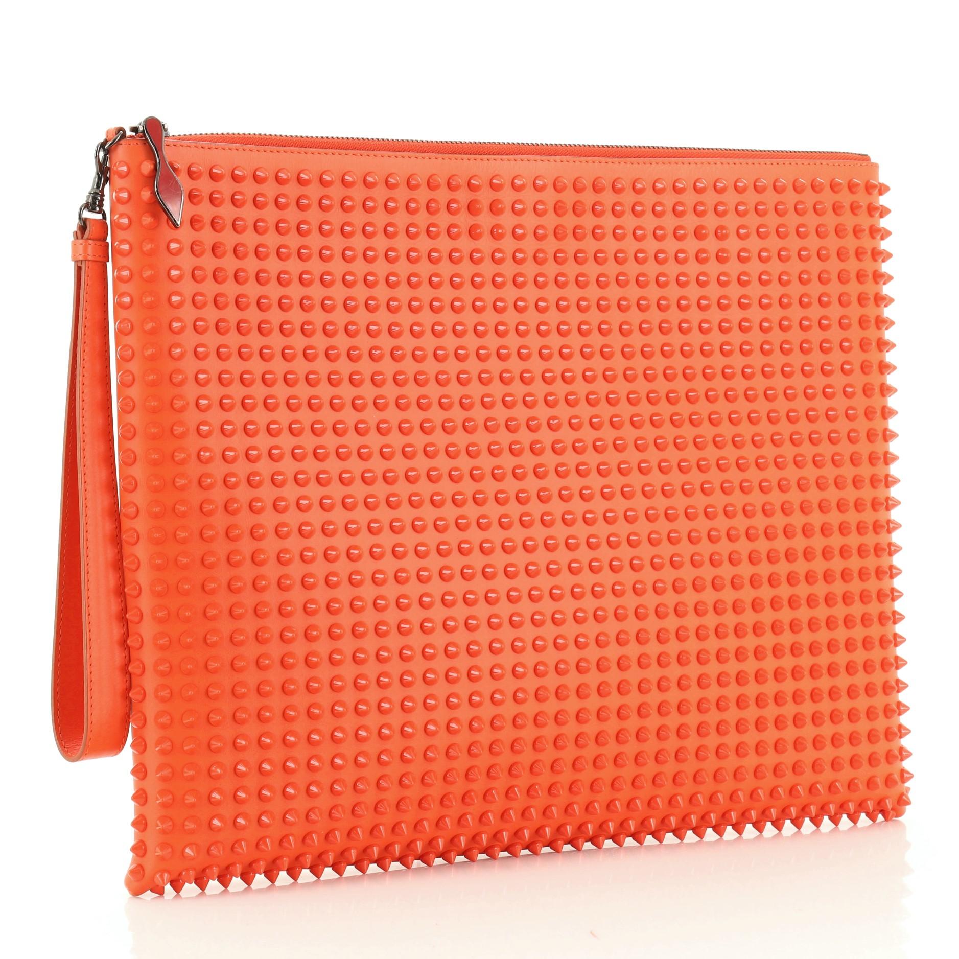 This Christian Louboutin Peter Pouch Spiked Leather Medium, crafted from orange spiked leather, features a wristlet strap, exterior back zip pocket, and gunmetal-tone hardware. Its zip closure opens to a red fabric interior with multiple card slots