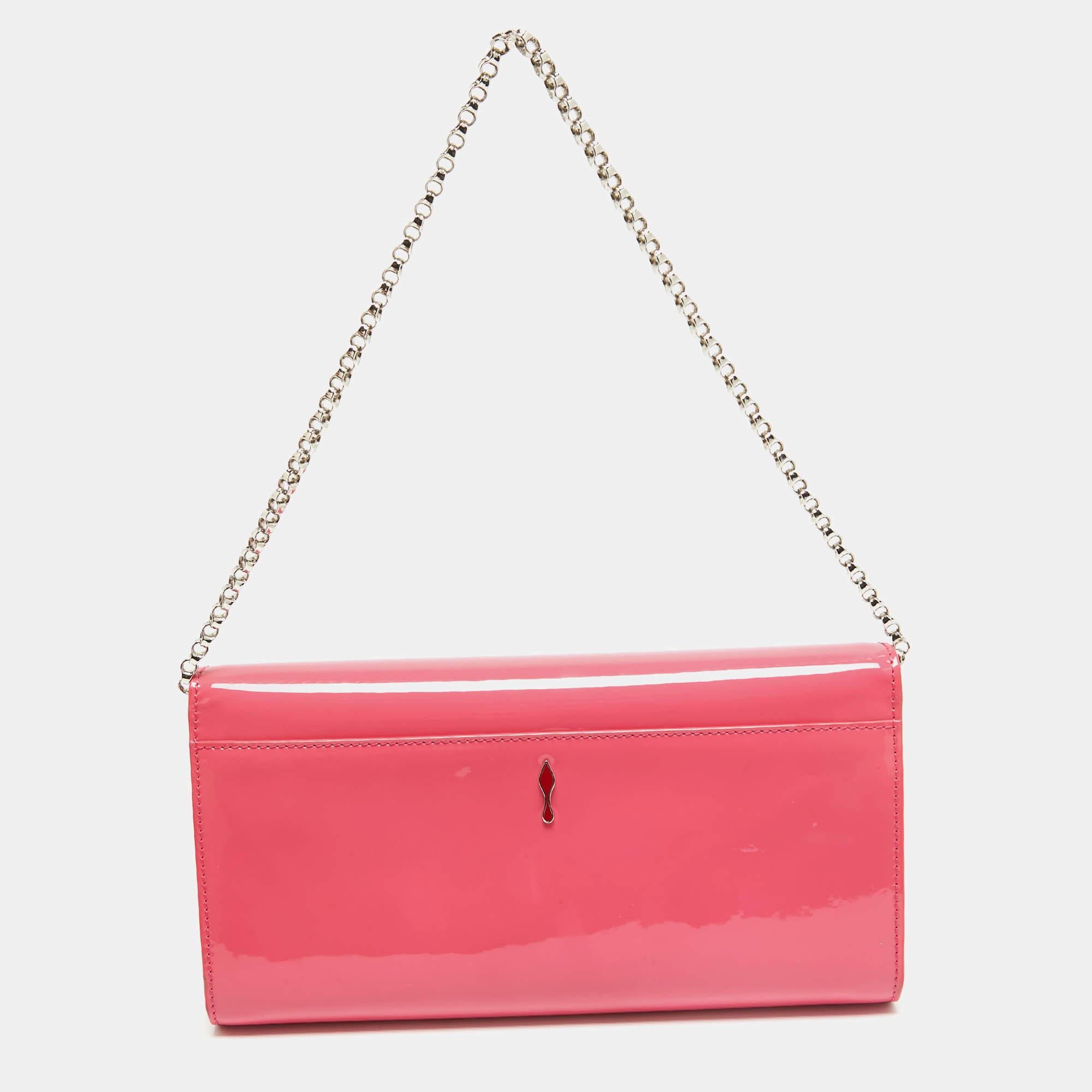 Crafted from patent leather and covered in a pink hue, this Christian Louboutin clutch has a style that will catch glances from a mile. It is designed with a flap that reveals a suede interior and it is held by a chain. The fashionable logo on the