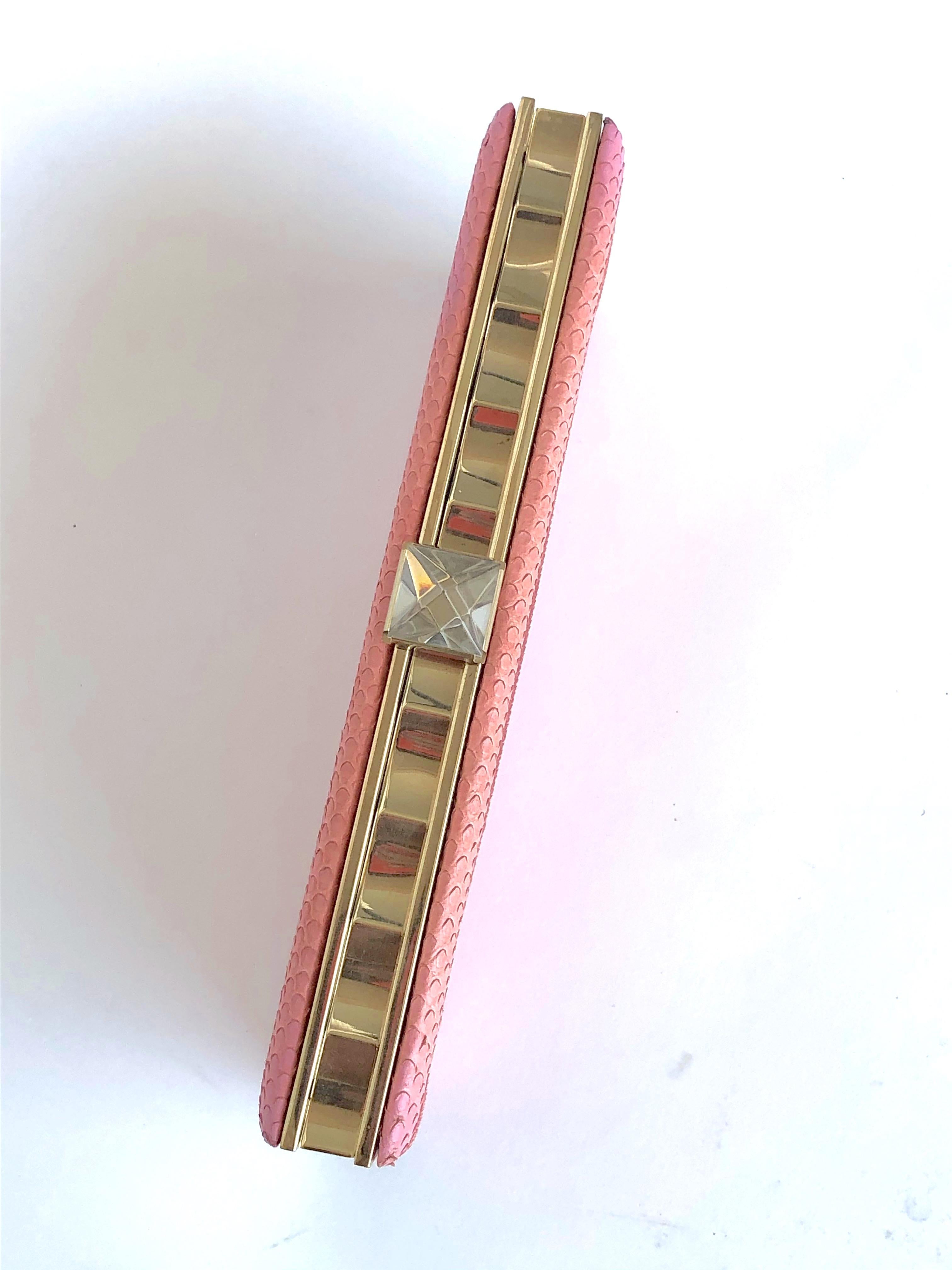 Pink snake skin upper. Gold-tone metal hardware. Curved metal frame. Clear crystal pyramid stud clasp detail. Red jacquard lining. Single pocket at interior. Gold-tone chain metal shoulder strap. Slight discoloration 