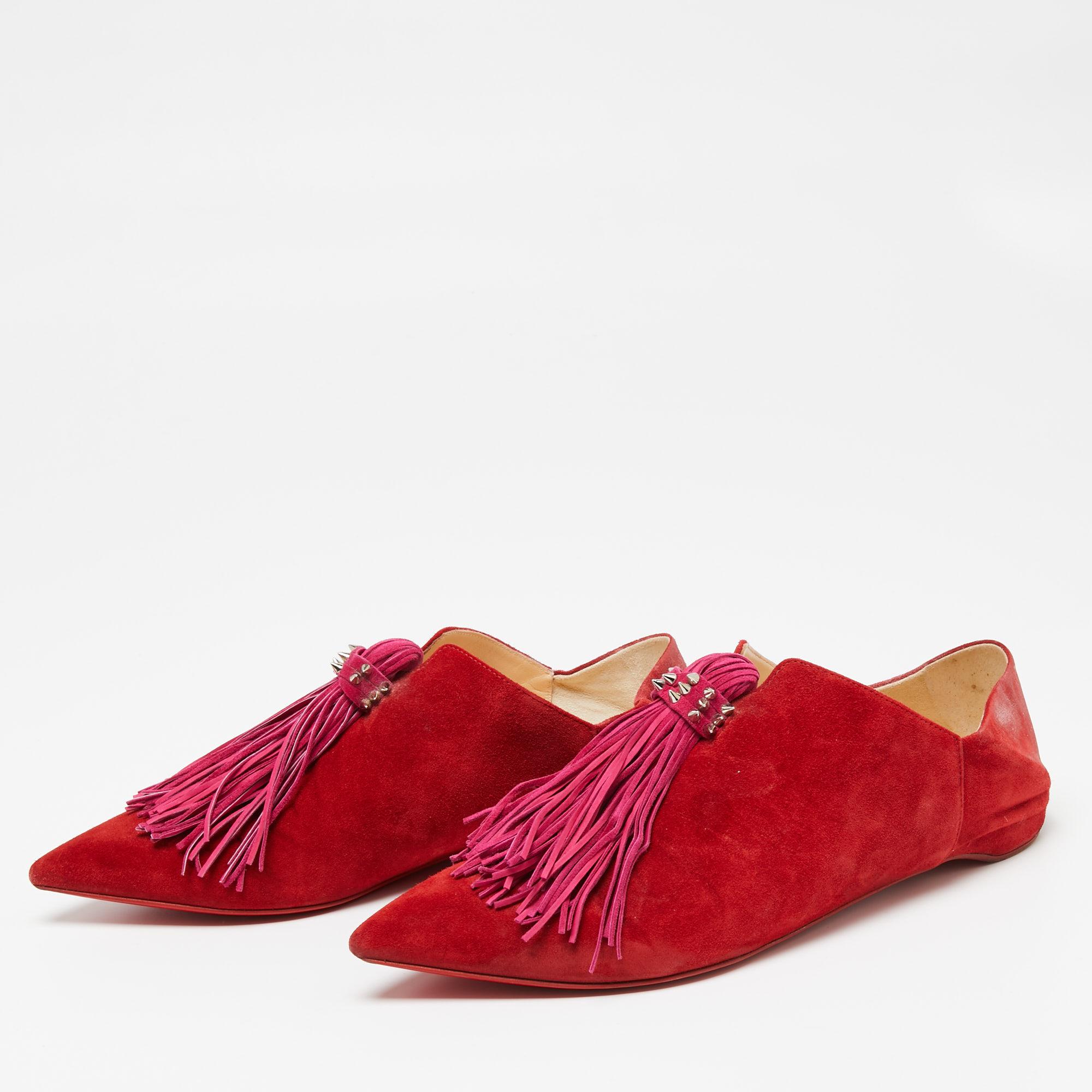 The oversized tassel design on the red upper of these Christian Louboutin sandals serves as a striking element. Crafted from suede into a pointed-toe silhouette, the silver-tone accents make them undeniably chic. The low heels and covered-up