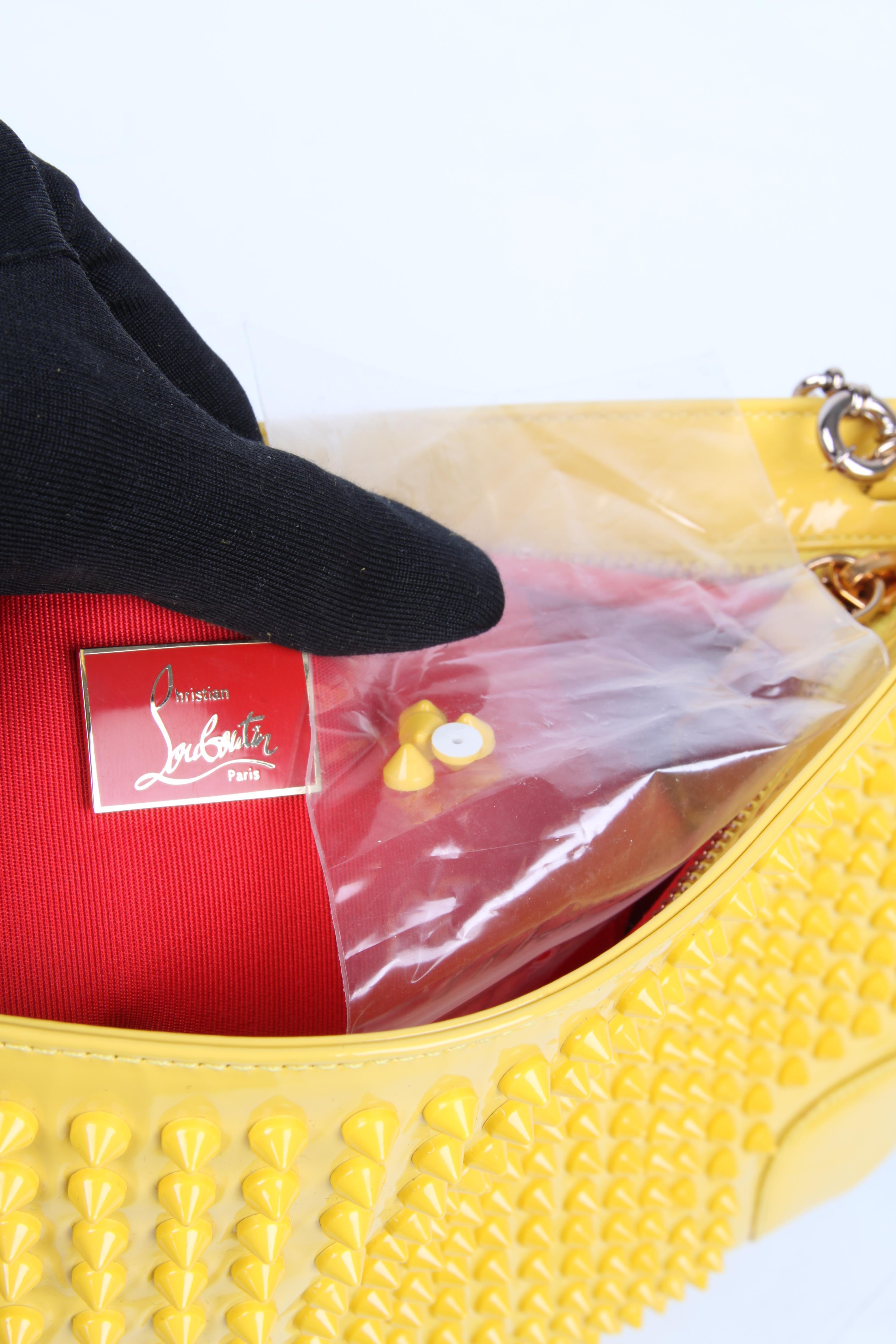 Outstanding yellow bag by Louboutin covered with studs.

This clutch has a rather large size and closes with a zipper on top. A removable silver-tone chain is also to be found there.

Inside lining of course in red fabric, one small flat pocket that