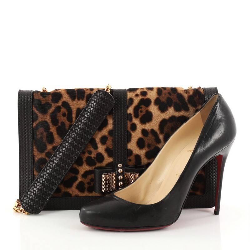 This authentic Christian Louboutin Sweet Charity Convertible Clutch Pony Hair Small showcases a stylish chic appeal. Constructed from leopard print pony hair, this petite bag features a long chain strap, decorative mesh bow on its flap, woven black