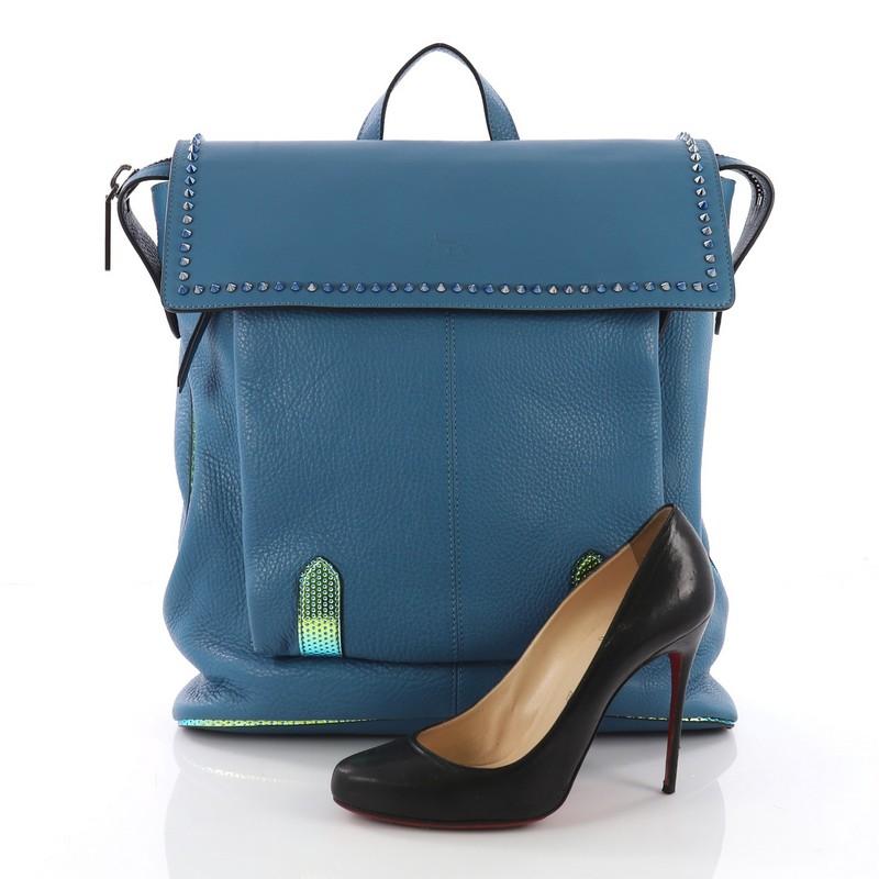 This Christian Louboutin Syd Flap Backpack Spiked Leather, crafted in blue spiked leather, features top leather handle, shoulder strap, front pocket under its flap and gunmetal-tone hardware. Its flap opens to a black fabric interior with zip and