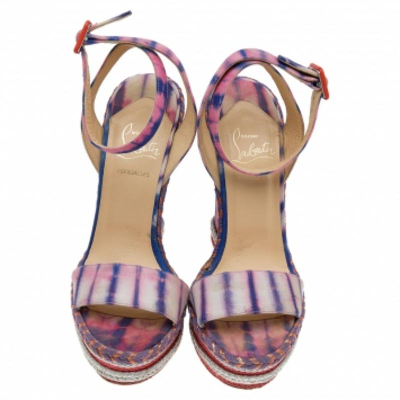 These sandals from the House of Christian Louboutin are pretty and poised. Made from multicolored fabric, these sandals flaunt platform wedge heels and an ankle strap feature. They are provided with buckled closure and red soles. Complement your