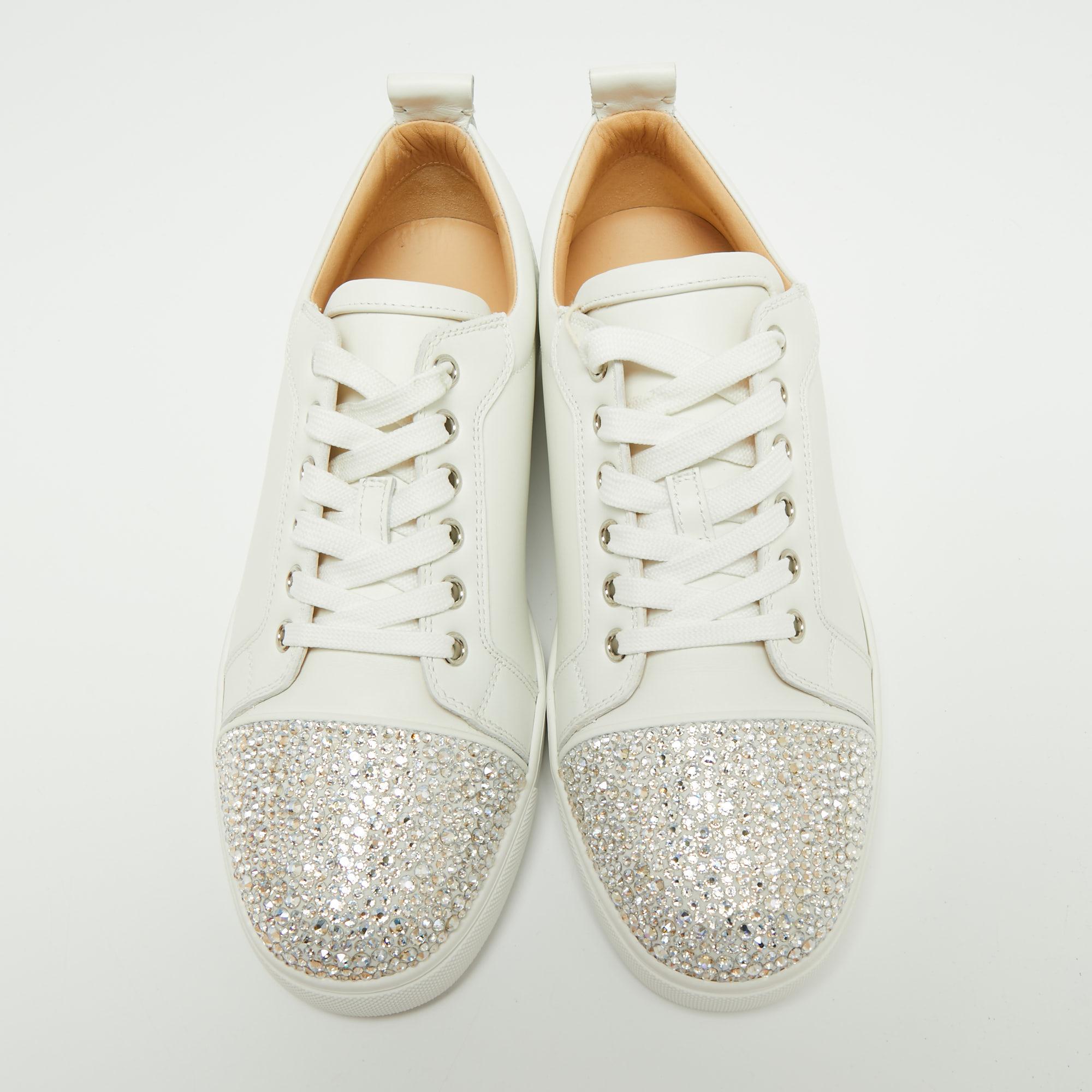 Enriched with striking elements, these Christian Louboutin sneakers have an eye-catching display. The design uses beautiful crystal embellishments on the front and a white leather exterior. The shoes are teamed with lace-up vamps, round toes, and