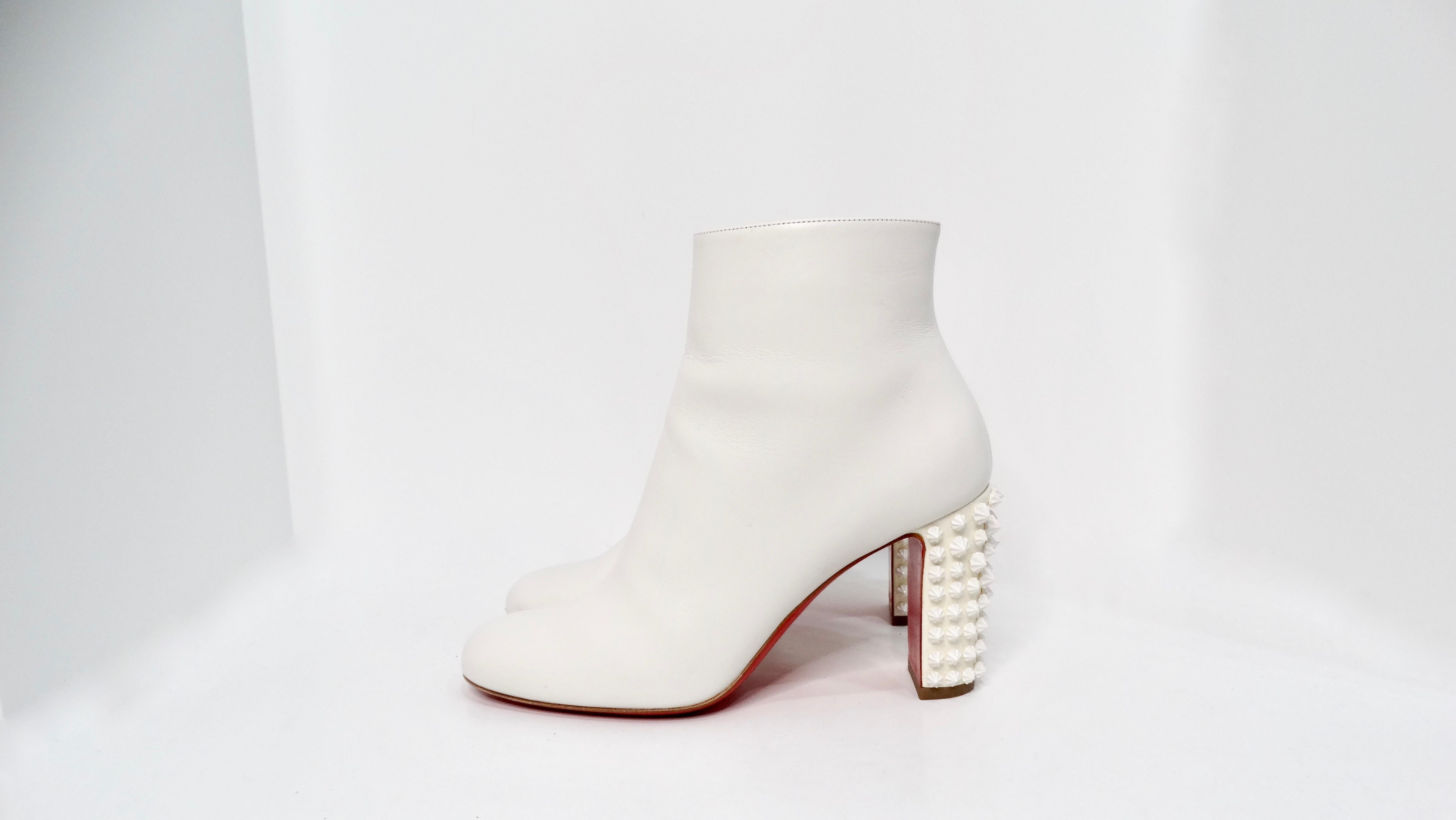 The Christian Louboutin White Suzi Folk Smooth Calfskin Ankle Boots are a striking blend of elegance and modern edge. Crafted from supple white calfskin, these ankle boots feature the iconic Louboutin red bottoms that make a bold statement with