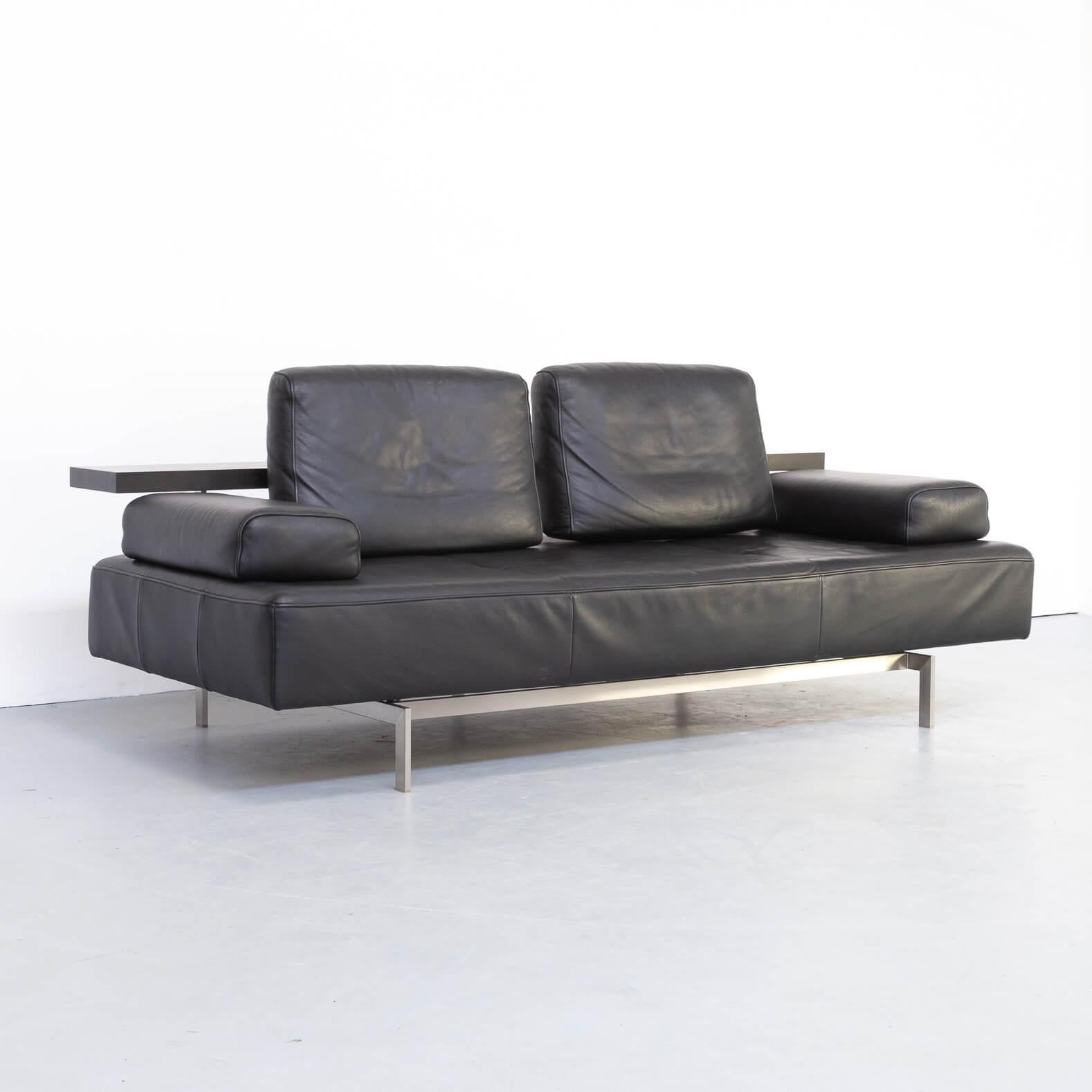 Christian Werner designed the DONO lounge sofa in 2004 and turned a daybed into a real comfortable sofa in beautiful design with optimal comfort. The all-round shelf is in dark oak veneer and together with the dull brushed stainless steel frame it