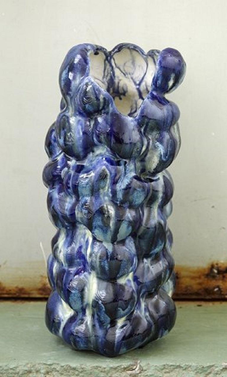 Christina Muff, Danish contemporary ceramicist (b. 1971).
Very tall and slim hand modelled sculptural vase that opens to one side in the top. Glazed in every shade of blue on the exterior. It has been fired numerous times to achieve this effect.