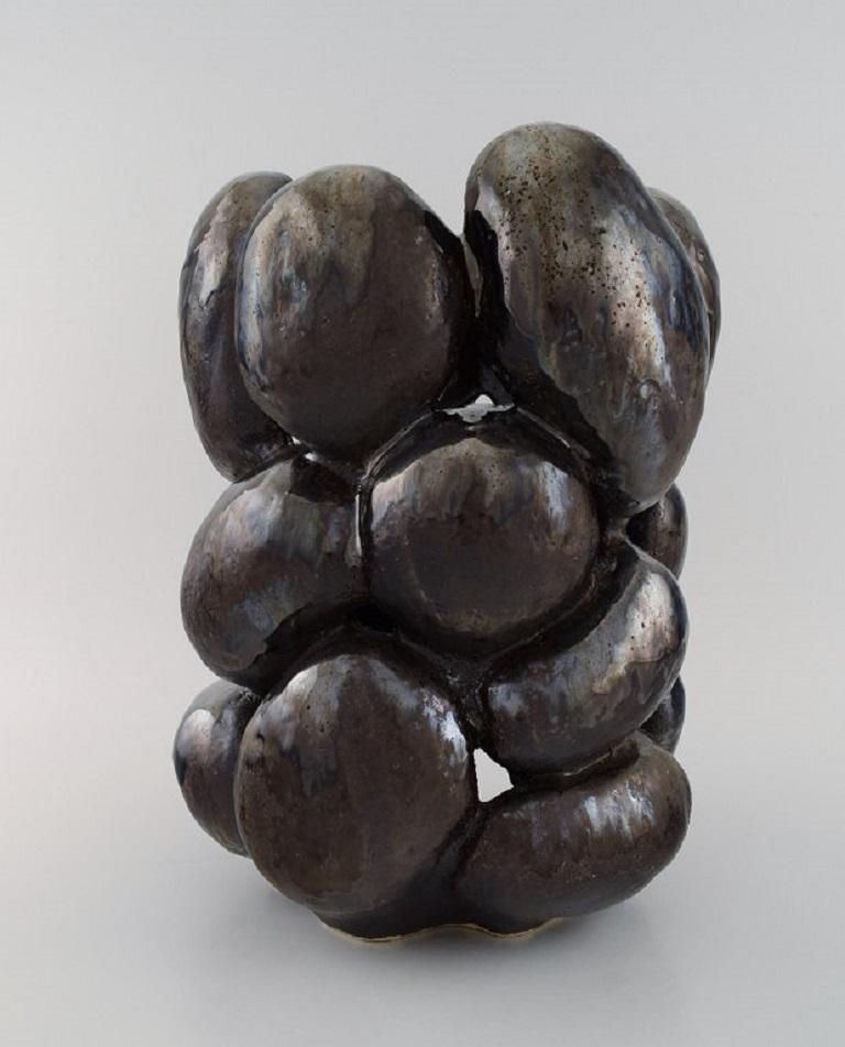 Christina Muff, ceramista contemporánea danesa (n. 1971). 
Gran jarrón escultórico único de gres esmaltado. Bonito esmalte metálico negro.
Medidas: 33 x 26 cm.
En excelente estado.
Firmado.

Técnica - Las formas de Christina Muff se modelan a
