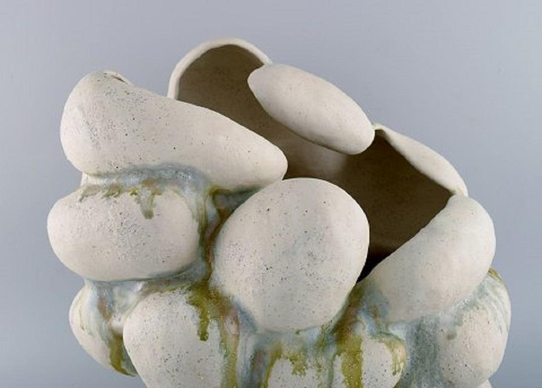 Christina Muff, Danish contemporary ceramicist (b. 1971). 
Hand-modelled sculptural vase of stoneware clay. 
The vessel is glazed with warm white glaze mixed with minerals from Danish beaches and ash glaze runs in blue and green. 
Part of the