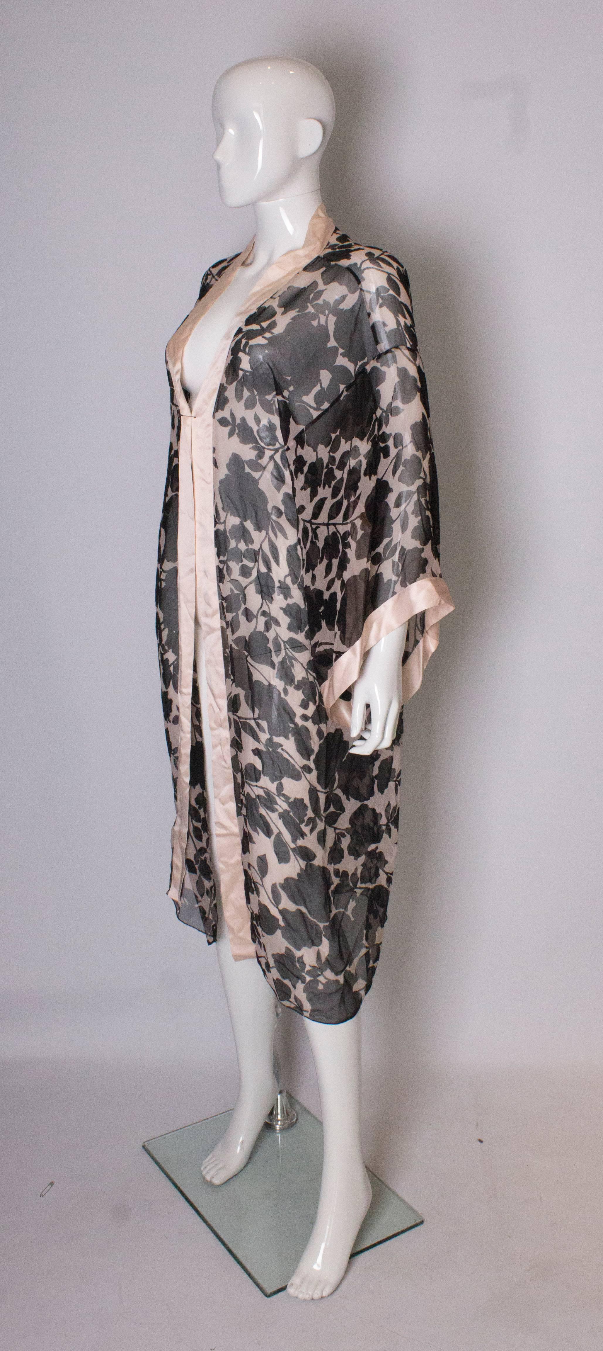 A chic,  vintage silk, satin edged kimono style gown. The fabric is  pink silk, with black flowers . It marked a size 38, loose fitting with bust up to 44'', length 48''