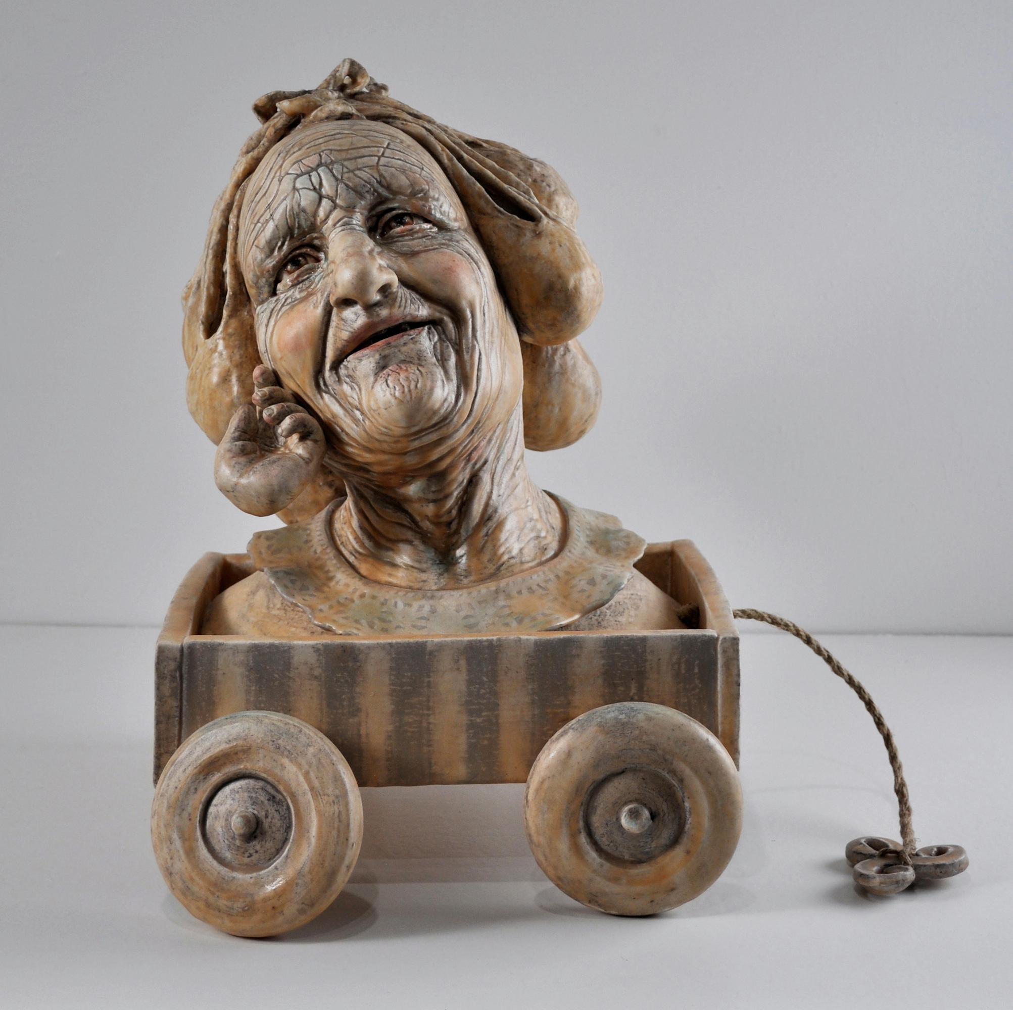 Christine Golden Figurative Sculpture - IN MEMORY OF TENDER CARESS- ceramic figurative sculpture of old woman in a wagon