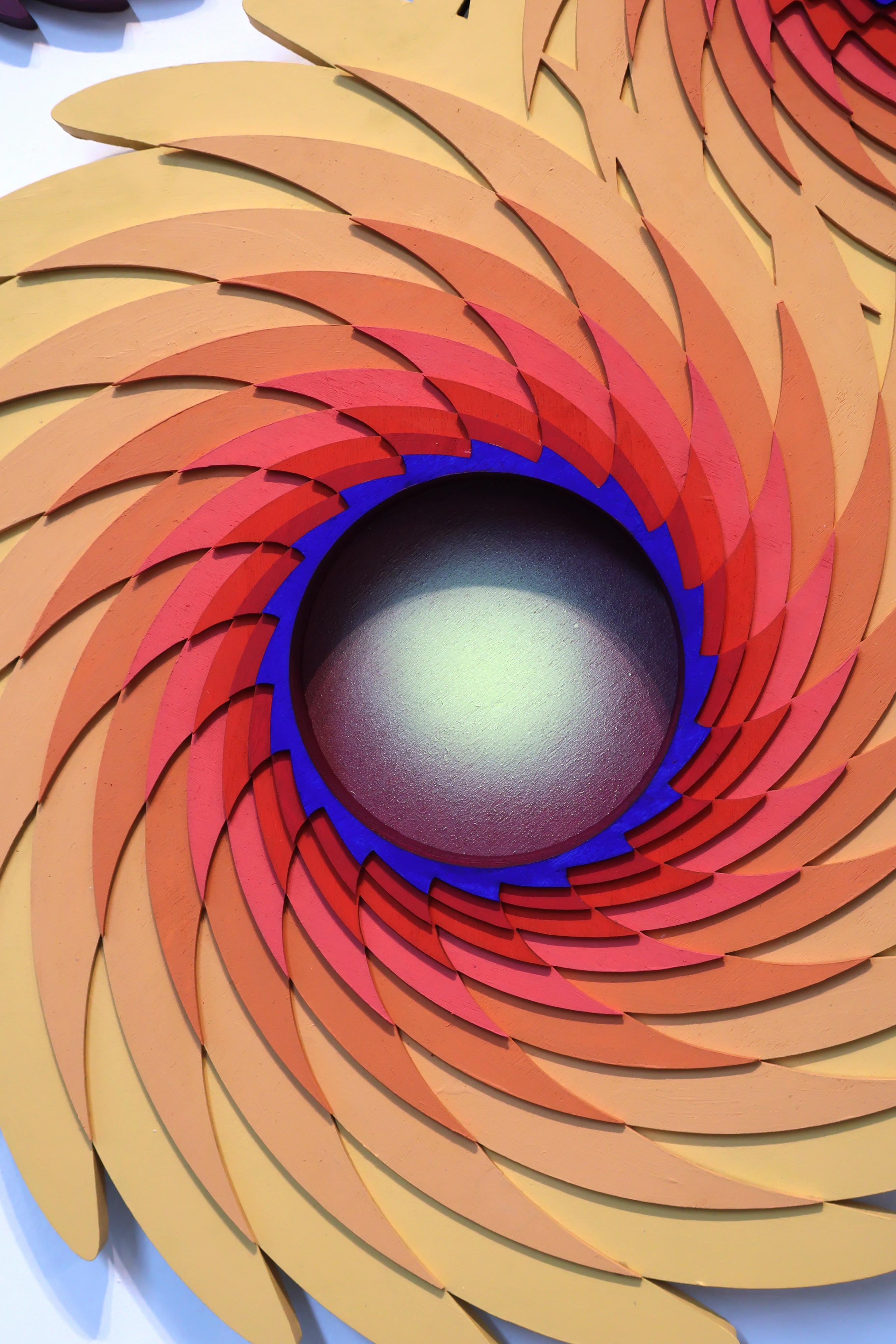 Questa sorprendente scultura geometrica da parete presenta forme intricate e vorticose che creano un senso ipnotico di movimento e profondità. Con un taglio preciso e forme radianti nelle calde tonalità dell'arancione, del rosso e del giallo,