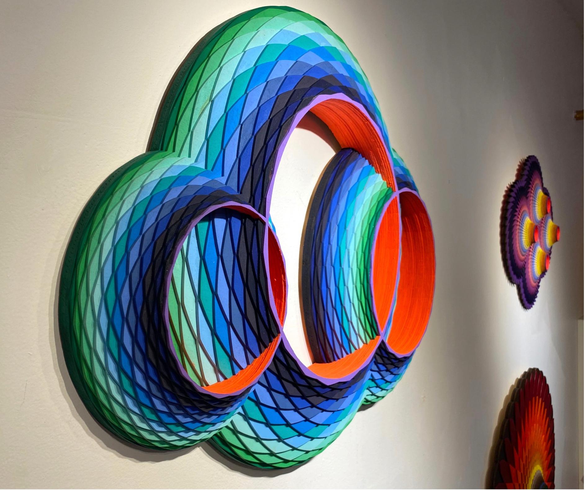 Multicolored circular geometric wall sculpture, acrylic on laser cut Wood by Christine Romanell. 
Hues of blue, orange, yellow, purple, swirls in geometric pattern with orange interior. 
Original signed by the artist on verso. Comes ready to