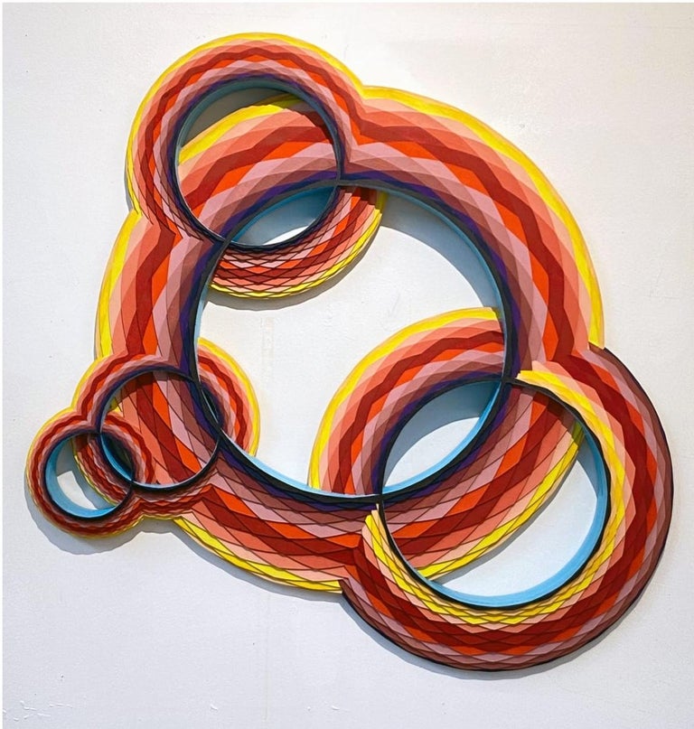 Multicolored circular geometric wall sculpture, acrylic on laser cut Wood by Christine Romanell.  
Hues of red, orange, yellow and pink swirls in geometric pattern with blue interior.  Original signed by the artist on verso. Comes ready to hang. 