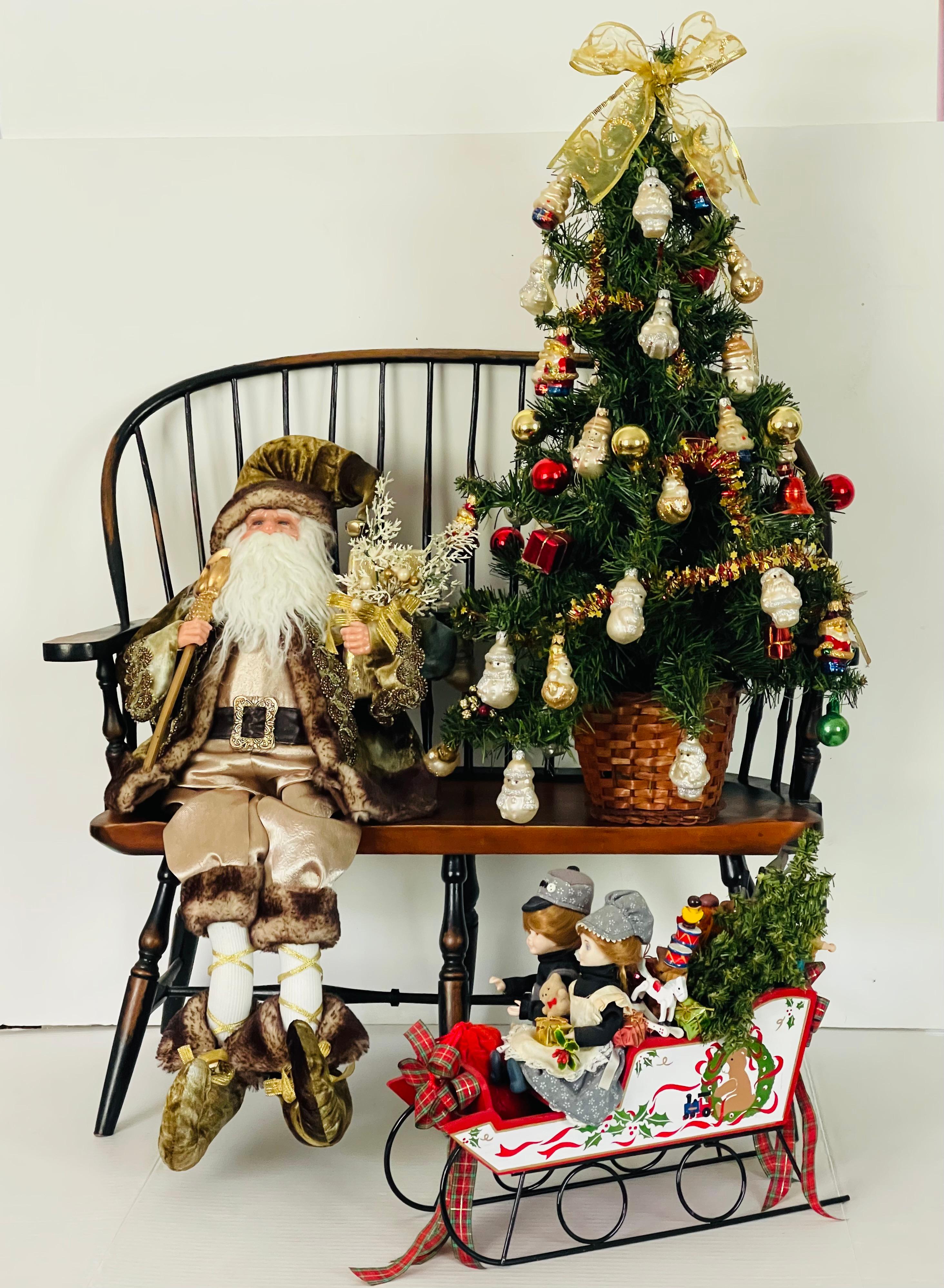Un'installazione natalizia unica nel suo genere, con panchina per bambini, Babbo Natale seduto e vestito di velluto, piccolo albero di Natale da 24 pollici decorato con ornamenti in vetro europeo e carro di giocattoli natalizi con giocattoli e