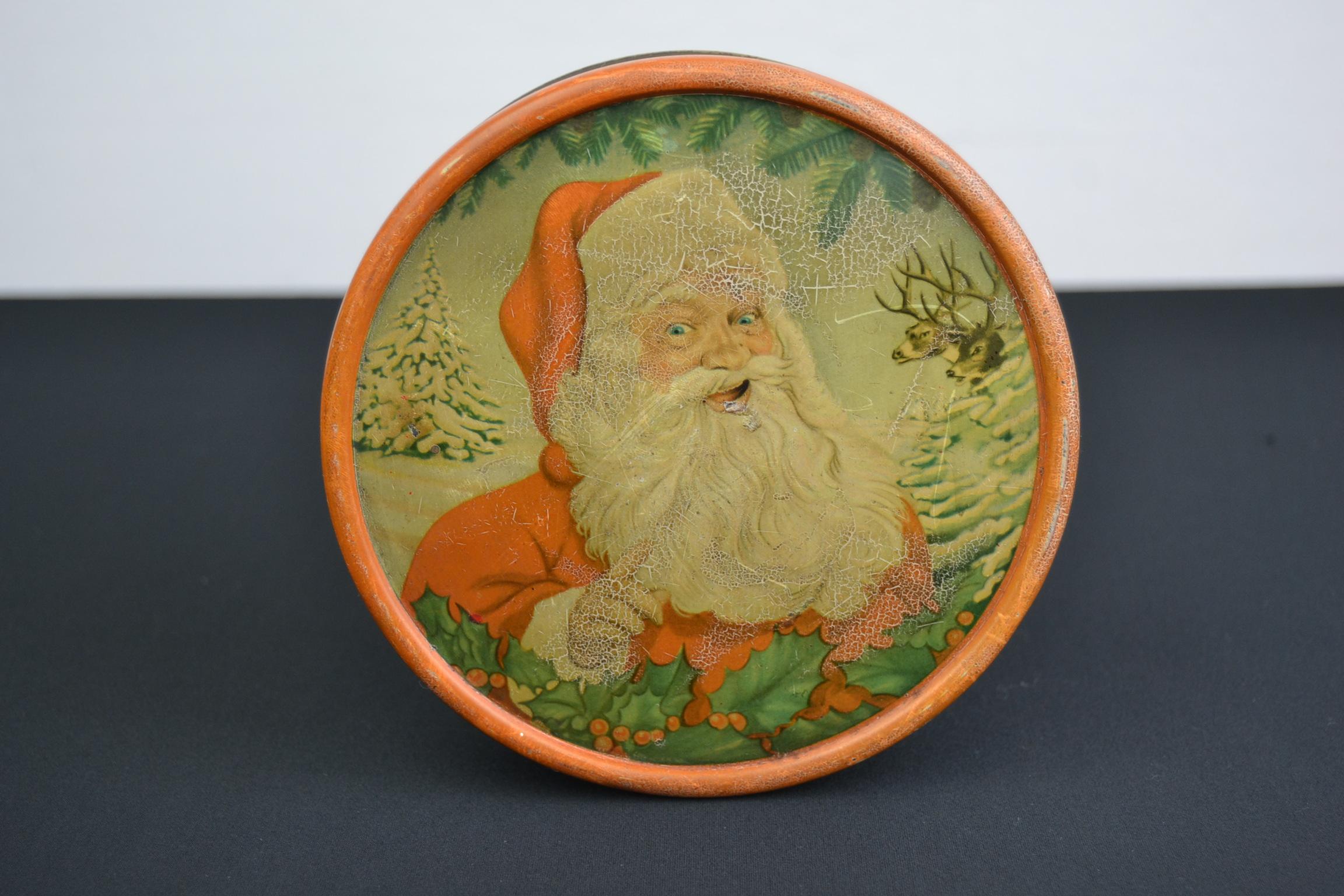 Belgian tin with Santa Claus on. This round tin with Christmas design was made for the confectionary brand M.F.G Demaret Brussels Belgium. On the lid you see Father Christmas, reindeer, Christmas trees and ilex. On the side you see more winter