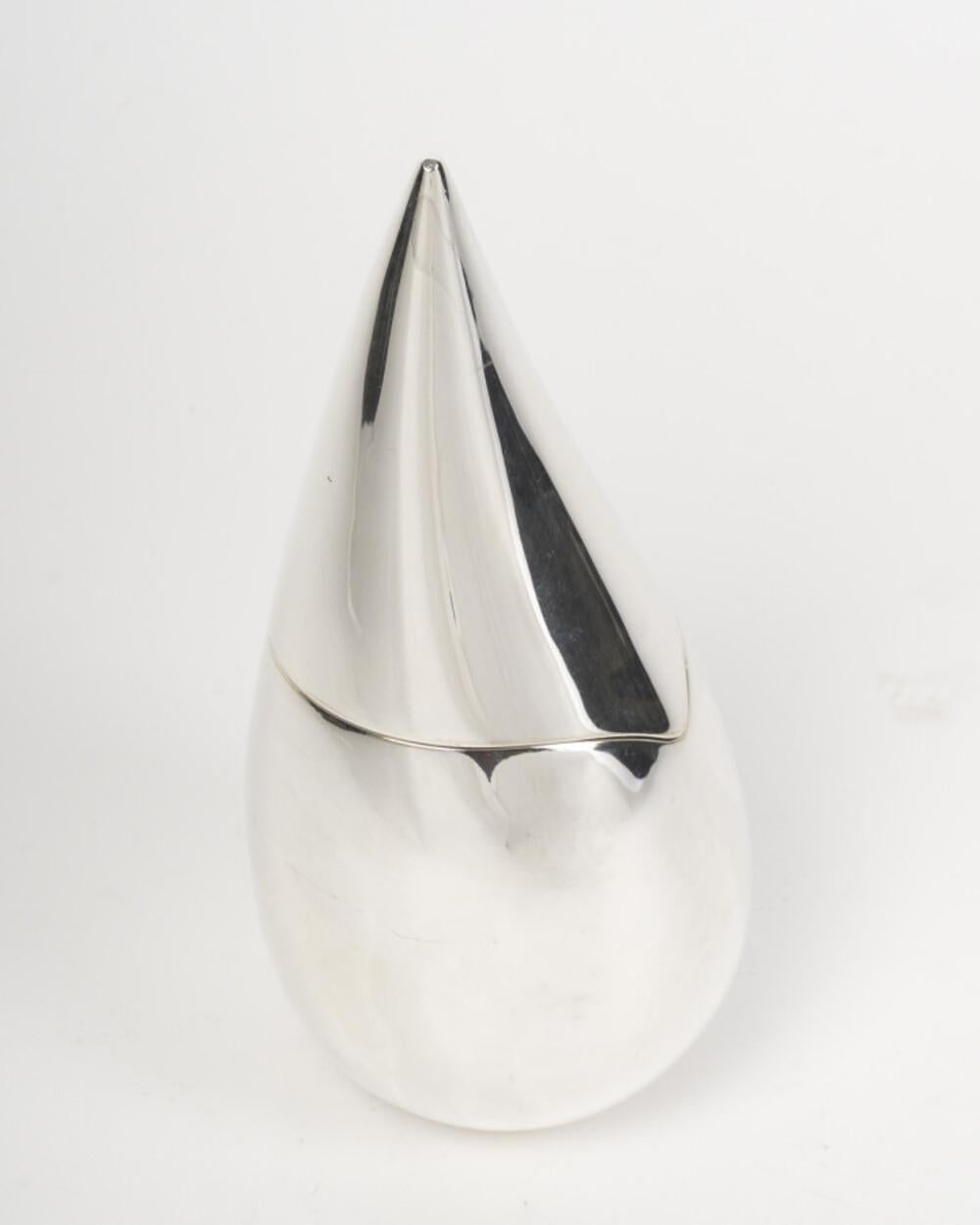 This solid silver piece adopts a modern and refined shape of a stylized water drop. Its smooth, slender, and symmetrical silhouette is marked by a very fine peak, giving it a sculptural elegance. This contemporary piece combines purity of line and