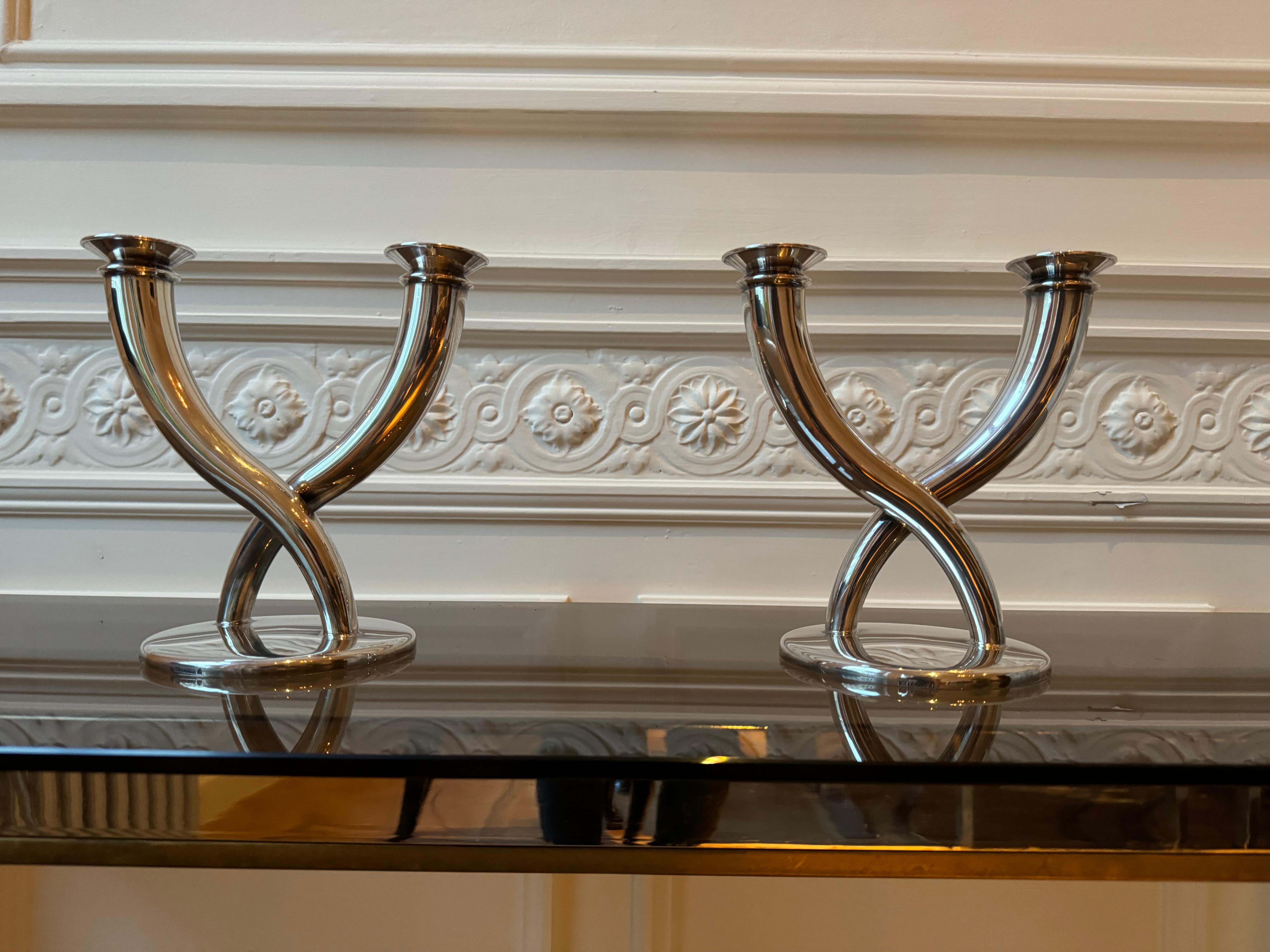 Pair of silver candelsticks designed by the famous Milanese architect and designer Gio Ponti. The candlesticks are two branches mounted on a round base, and they go upwards, slightly broadning towards the top, as they cross each other at around a