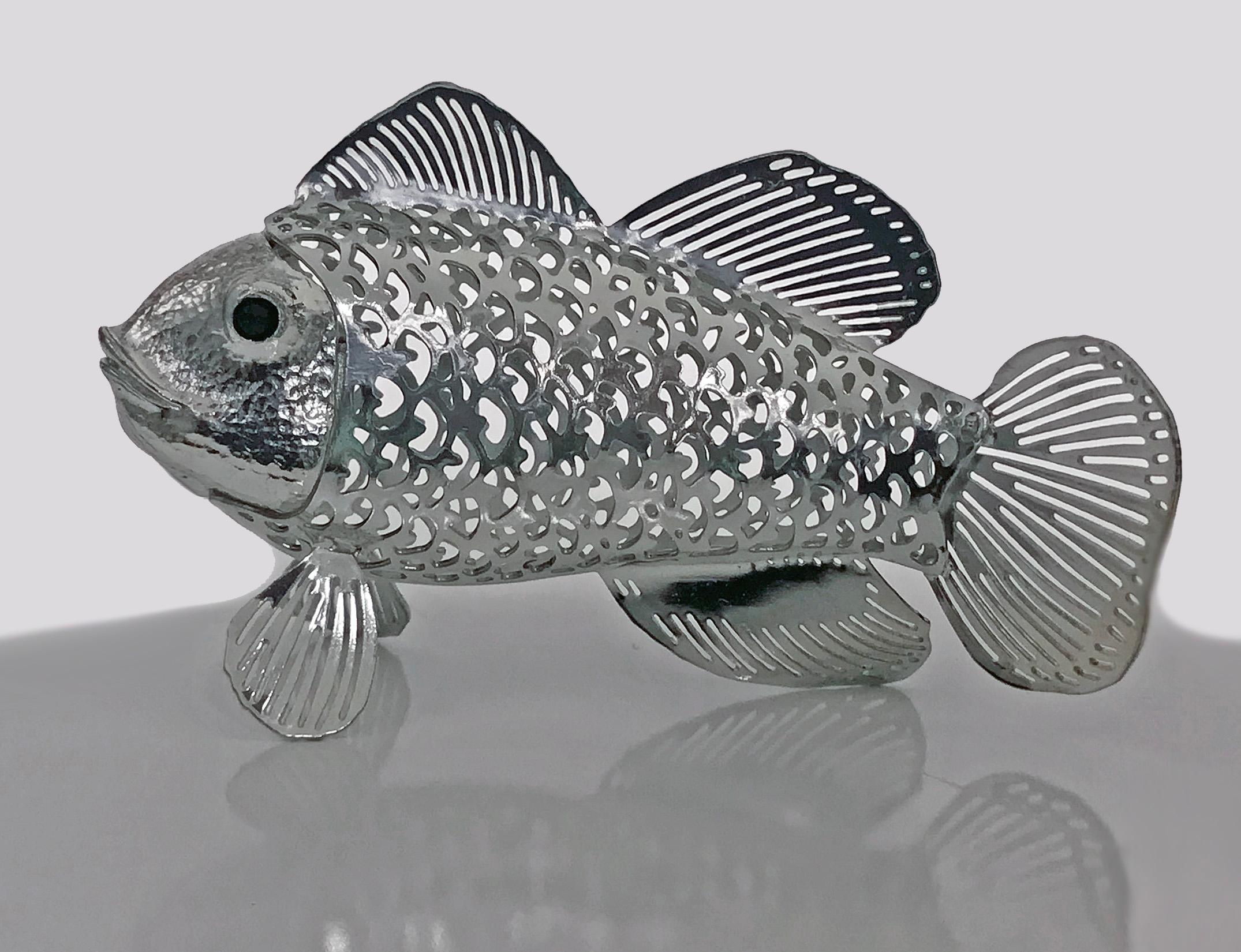 Figurine de poisson de la collection Lumiere de Christofle avec des yeux en onyx noir:: un corps et des nageoires réalistes en écailles percées. Mesures : 3.125 x 1::75 pouces. Marques complètes de Christofle.