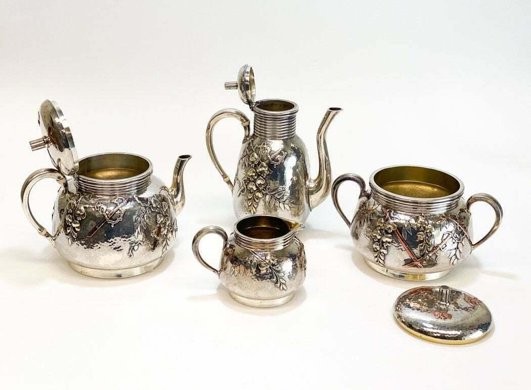An outstanding French .950 Japonism silver tea service by Christofle Orfevre, circa 1880. Spot hammered with applied decoration including gilt wisteria and copper bamboo, the covers of the teapot and sugar bowl each with three applied copper