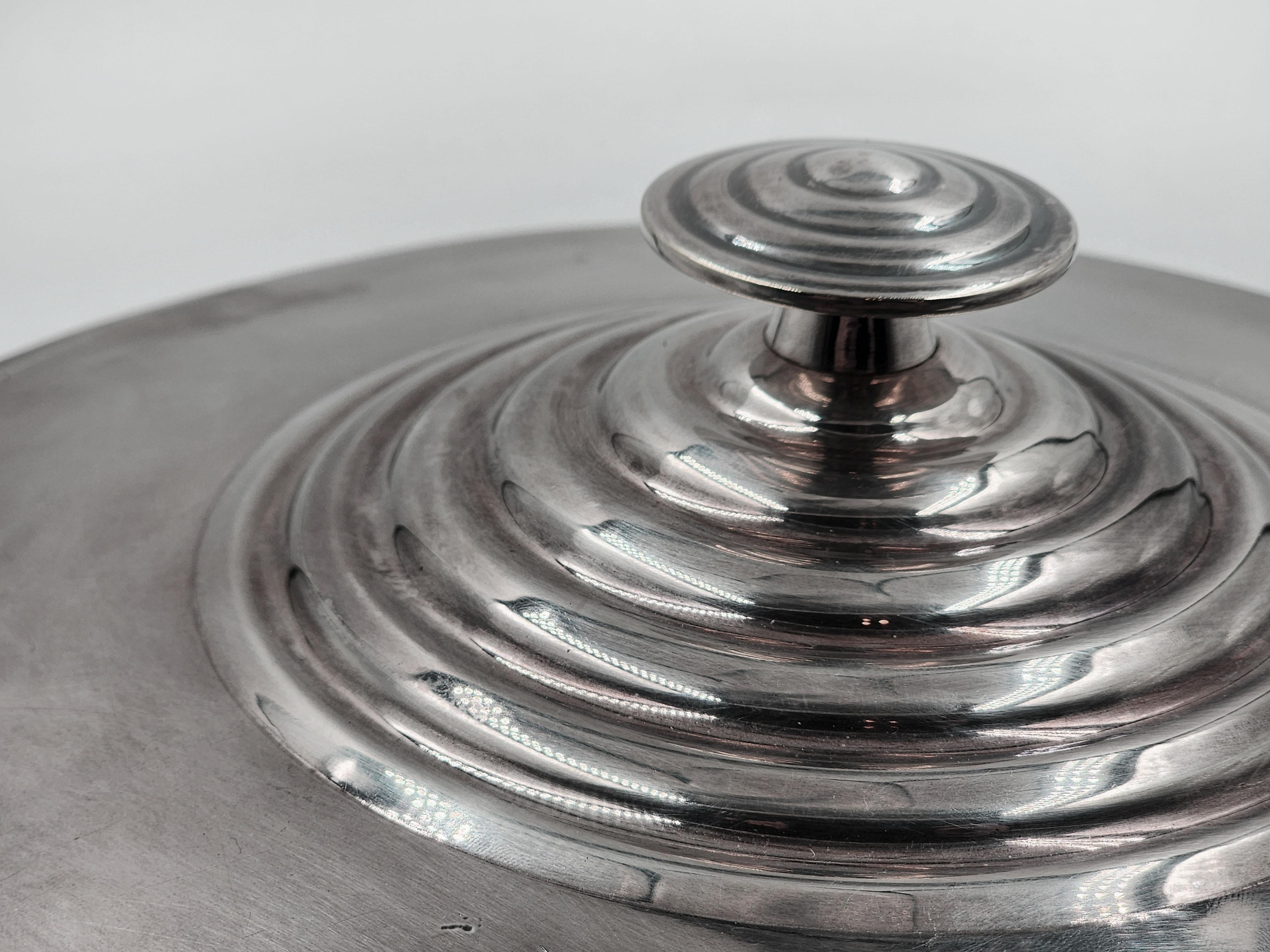 Casseruola Christofle Art Deco in metallo argentato
Questa casseruola in metallo argentato è un magnifico esempio dello stile Art Déco, un movimento che ha segnato l'estetica degli anni Venti e Trenta. Il pezzo ha una forma circolare e robusta, con