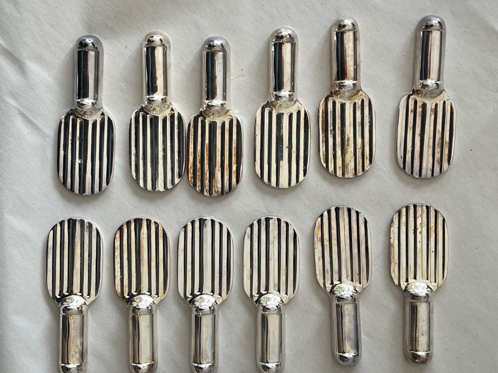 A stylish set of twelve (12) knife rests by Christofle. In two original boxes, made in France ca' 1960's, silverplate. In the shape of a racquet.
