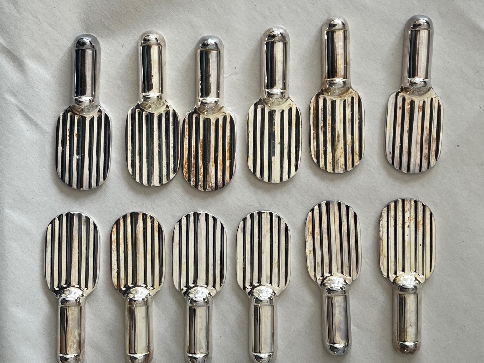A stylish set of twelve (12) knife rests by Christofle. In two original boxes, made in France ca' 1960's, silverplate. In the shape of a racquet.